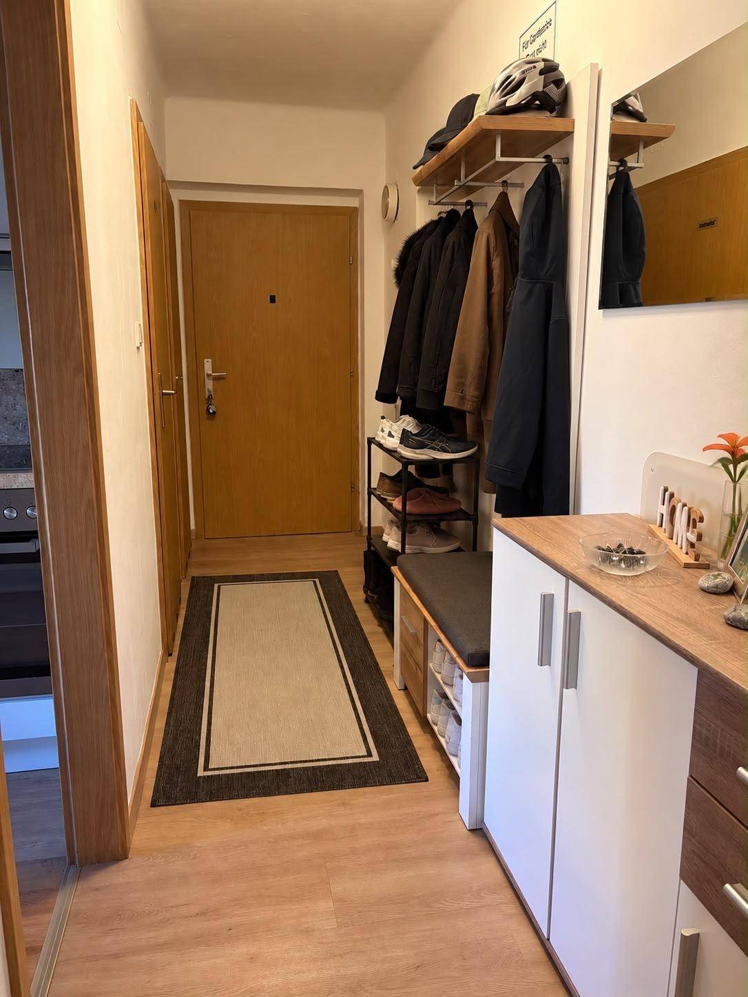 Heller Eingangsbereich mit Garderobe, Schuhregal und praktischem Schrank.