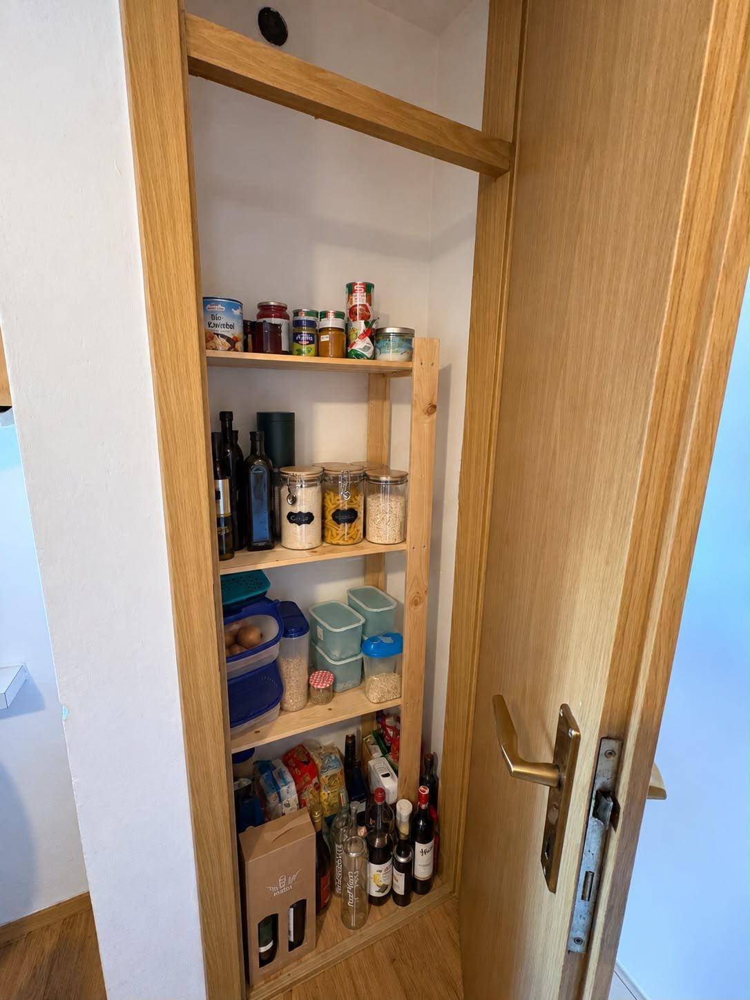 Praktische Speisekammer mit Holzregalen und Vorräten für den Haushalt.