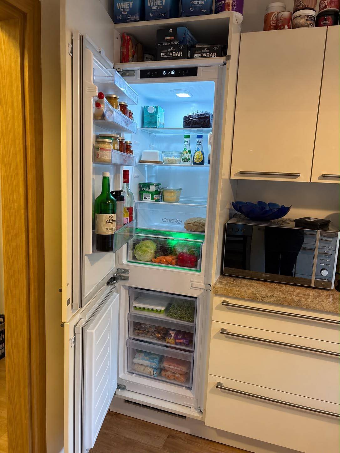 Offener Kühlschrank mit frischen Lebensmitteln, integriert in die Küchenzeile.