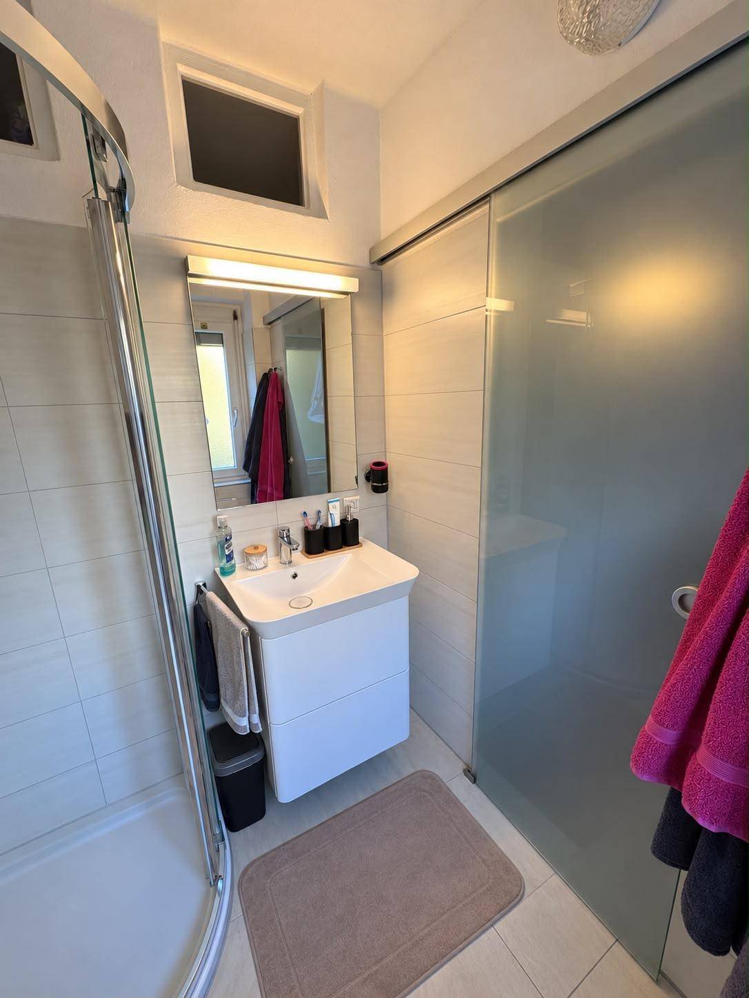 Modernes Badezimmer mit Duschkabine, Waschbecken und Spiegelschrank.