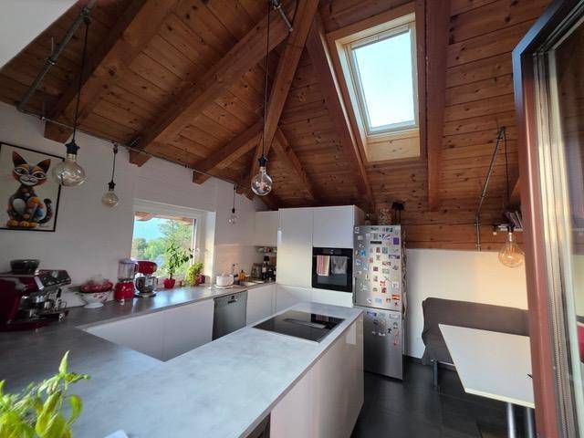 Moderne Küche mit Kochinsel, Einbaugeräten und rustikaler Holzbalkendecke.
