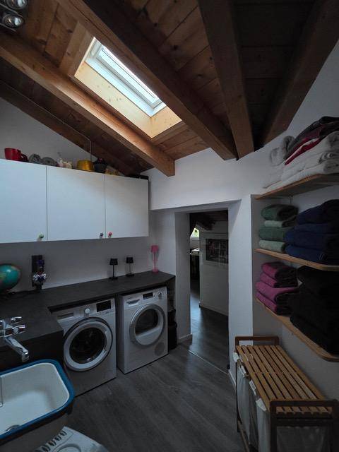 Praktischer Hauswirtschaftsraum mit Waschmaschinen, Spülbecken und natürlichem Licht durch Dachfenster.