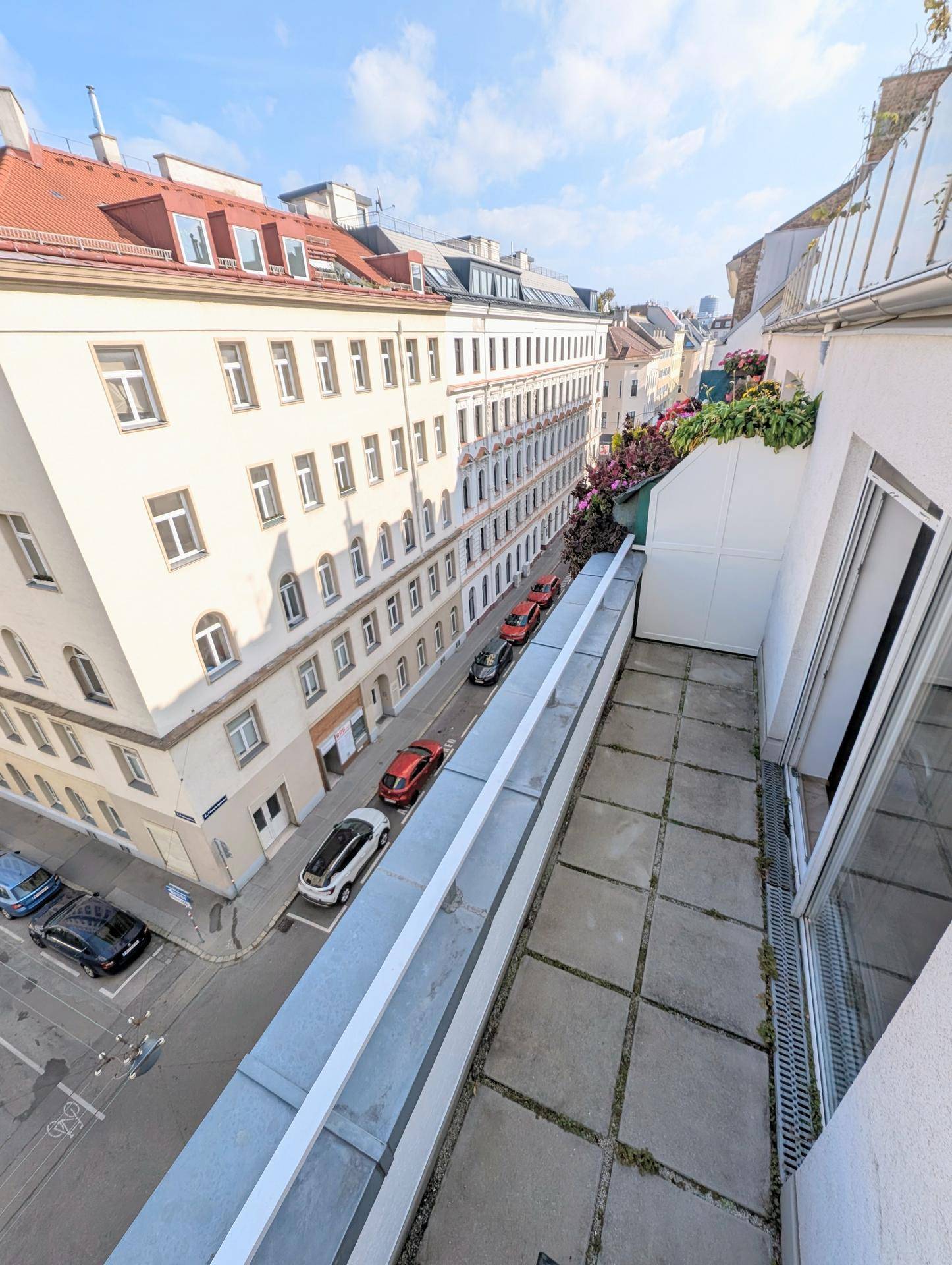 Langer Balkon mit Fliesenboden und weitem Blick auf die belebte Straße und die historischen Stadtgebäude.
