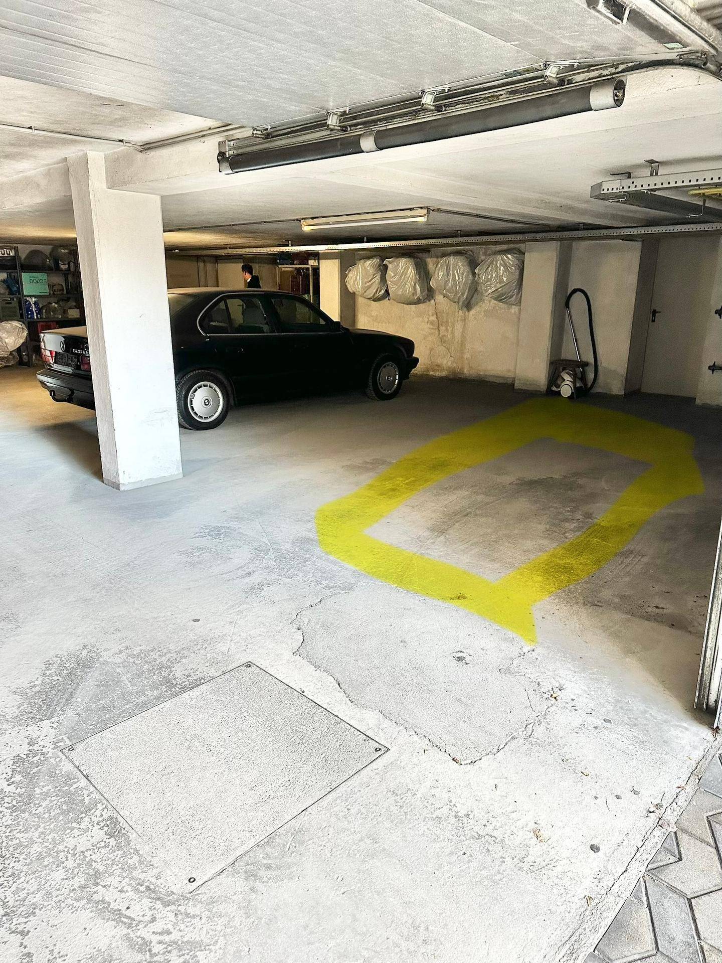 Tiefgarage mit Betonboden und einem markierten Parkplatz, bietet geschützten Stellplatz für Fahrzeuge.