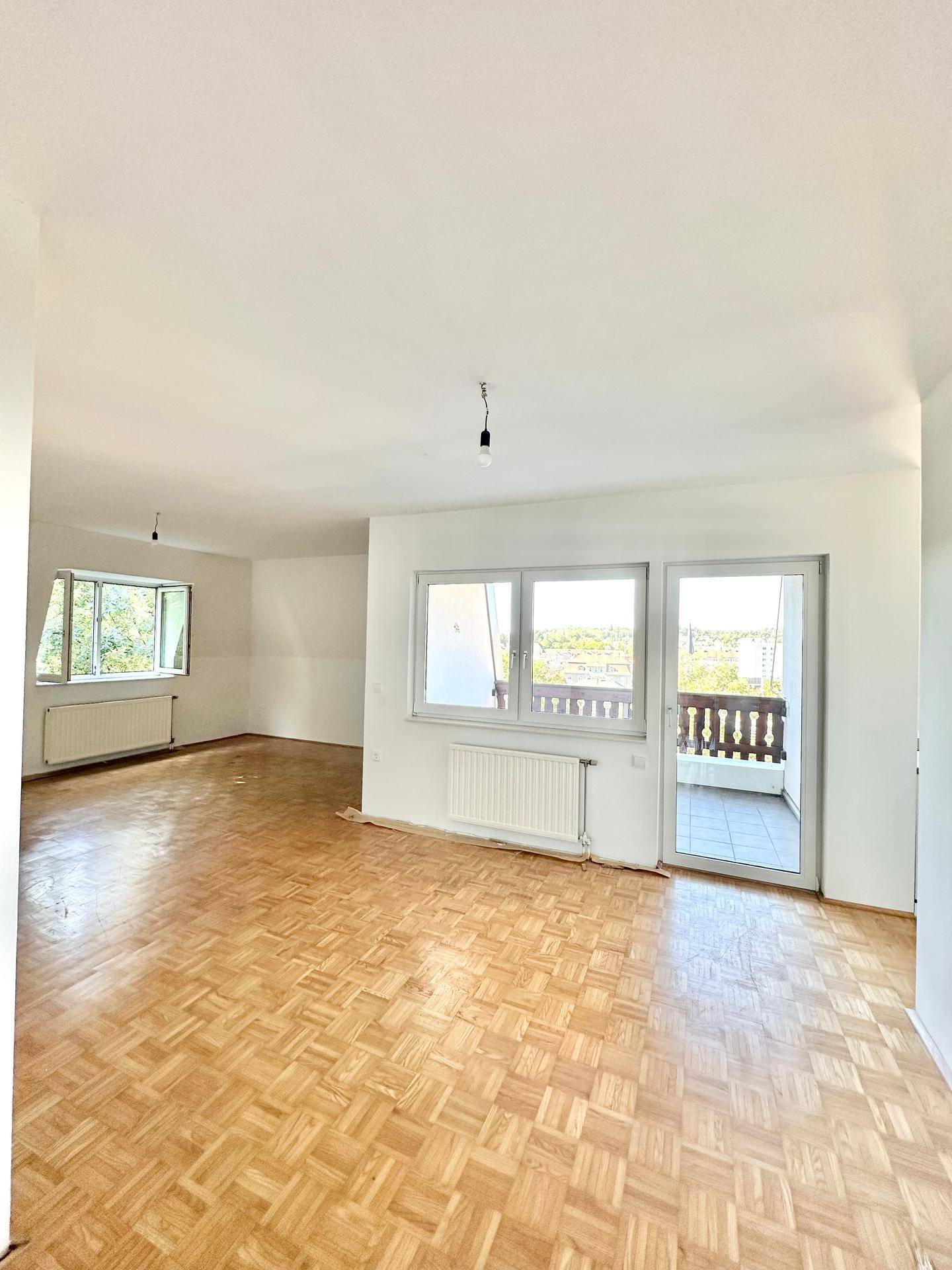 Helles Wohnzimmer mit Fischgrätparkettboden und Zugang zu einem Balkon, bereit zur individuellen Gestaltung.