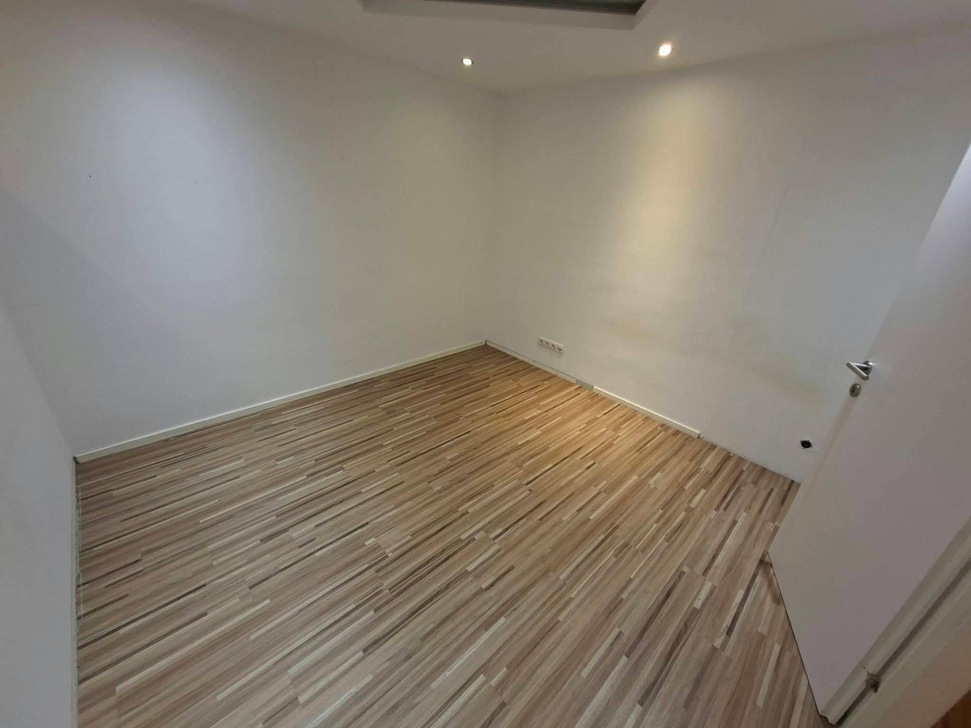 Helles Zimmer mit Laminatboden und Deckenstrahlern, ideal für Schlaf- oder Gästezimmer.
