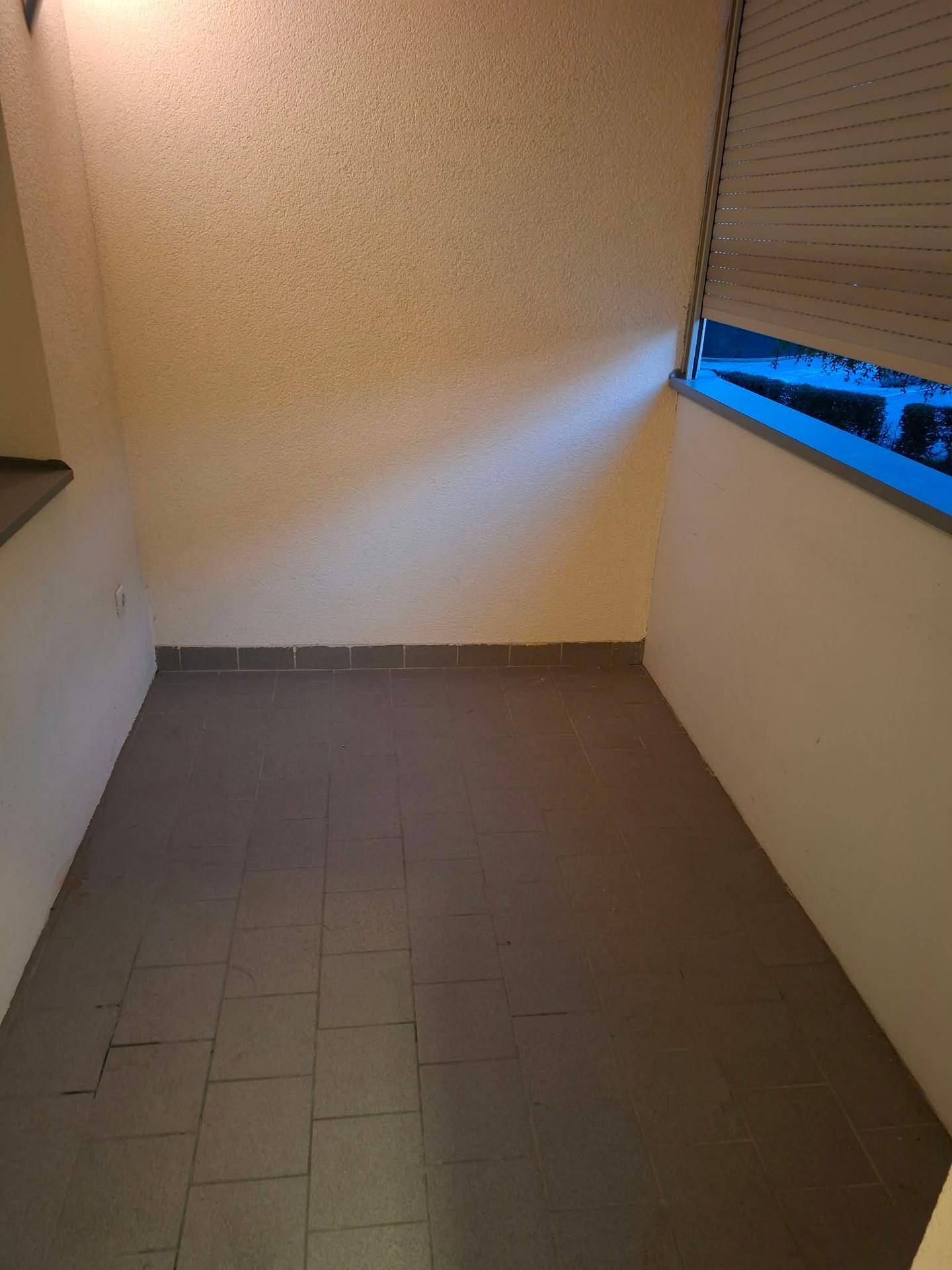 Kleiner gefliester Balkon mit Rollladen, bietet einen privaten Außenbereich.
