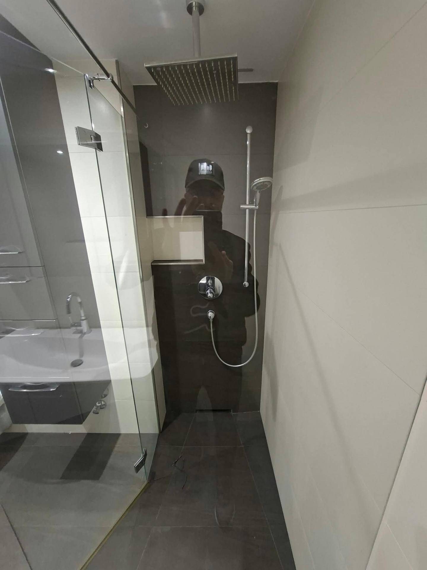 Moderne begehbare Dusche mit Regenduschkopf und Glasabtrennung in einem stilvollen Badezimmer.