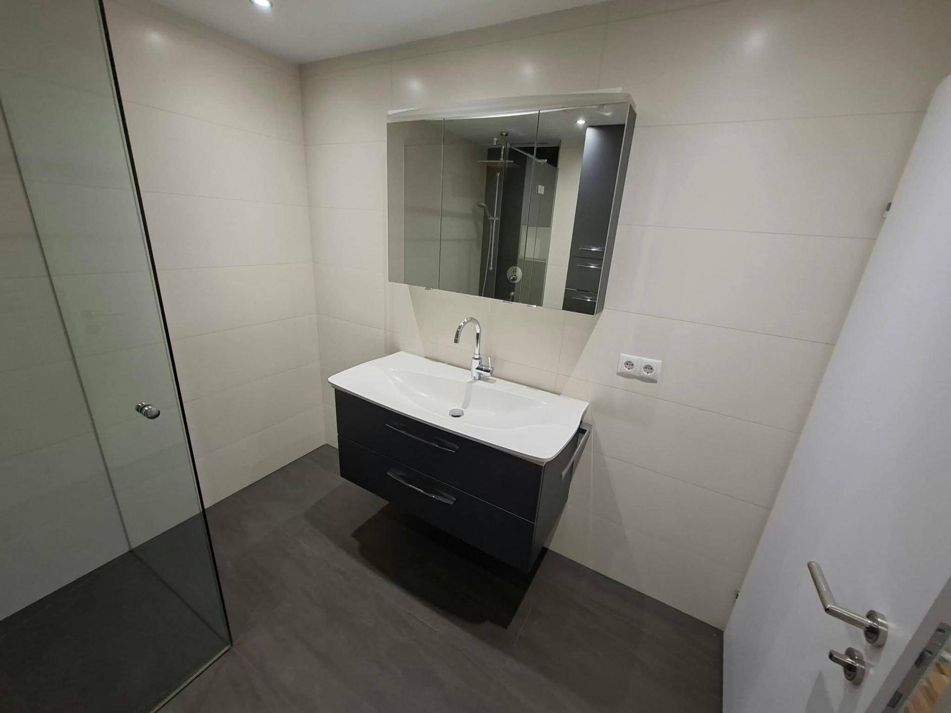 Modernes Badezimmer mit Waschtisch, Spiegelschrank und begehbarer Dusche.