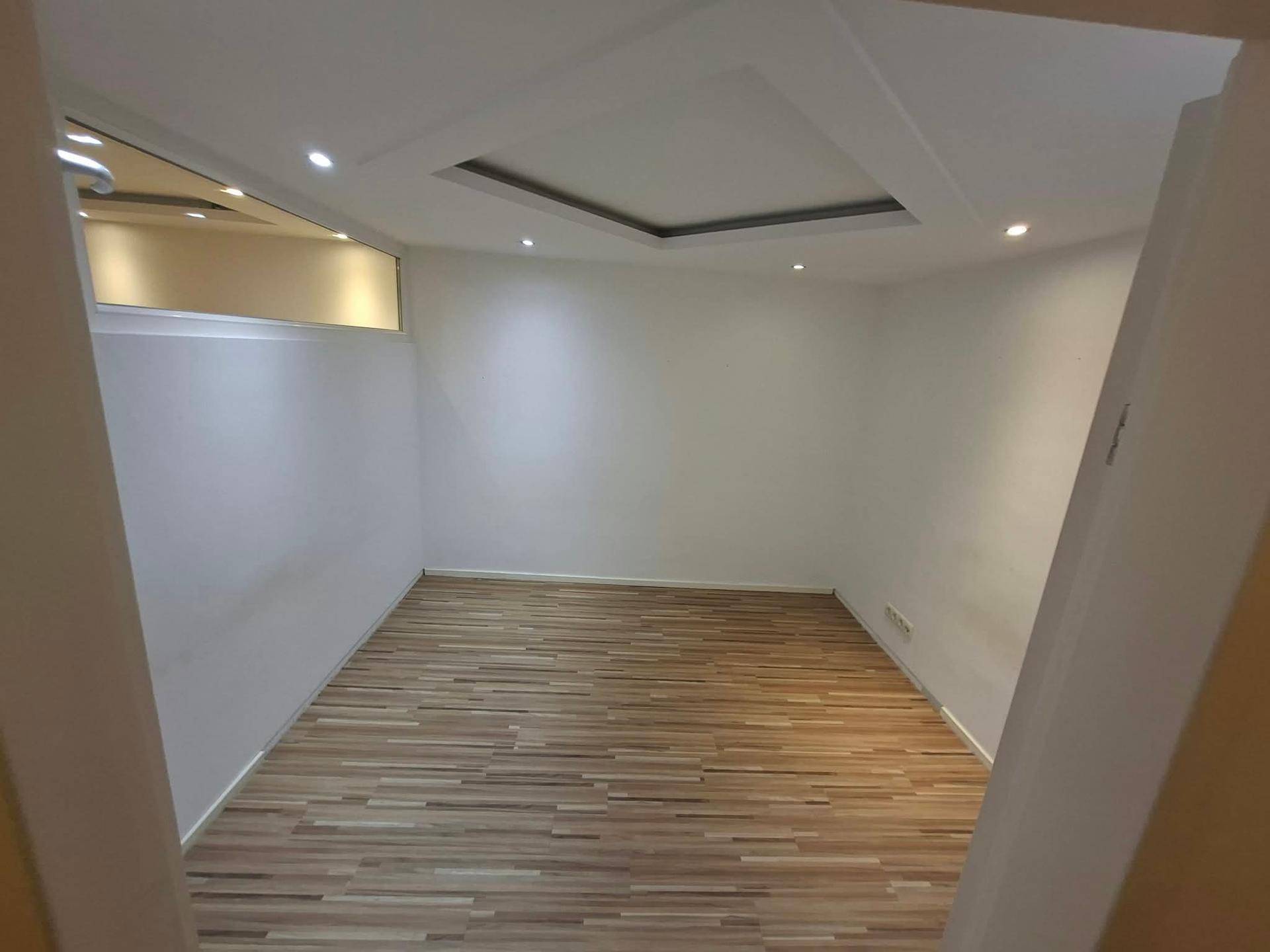 Helles Zimmer mit Laminatboden und moderner Deckenbeleuchtung, vielseitig nutzbar.