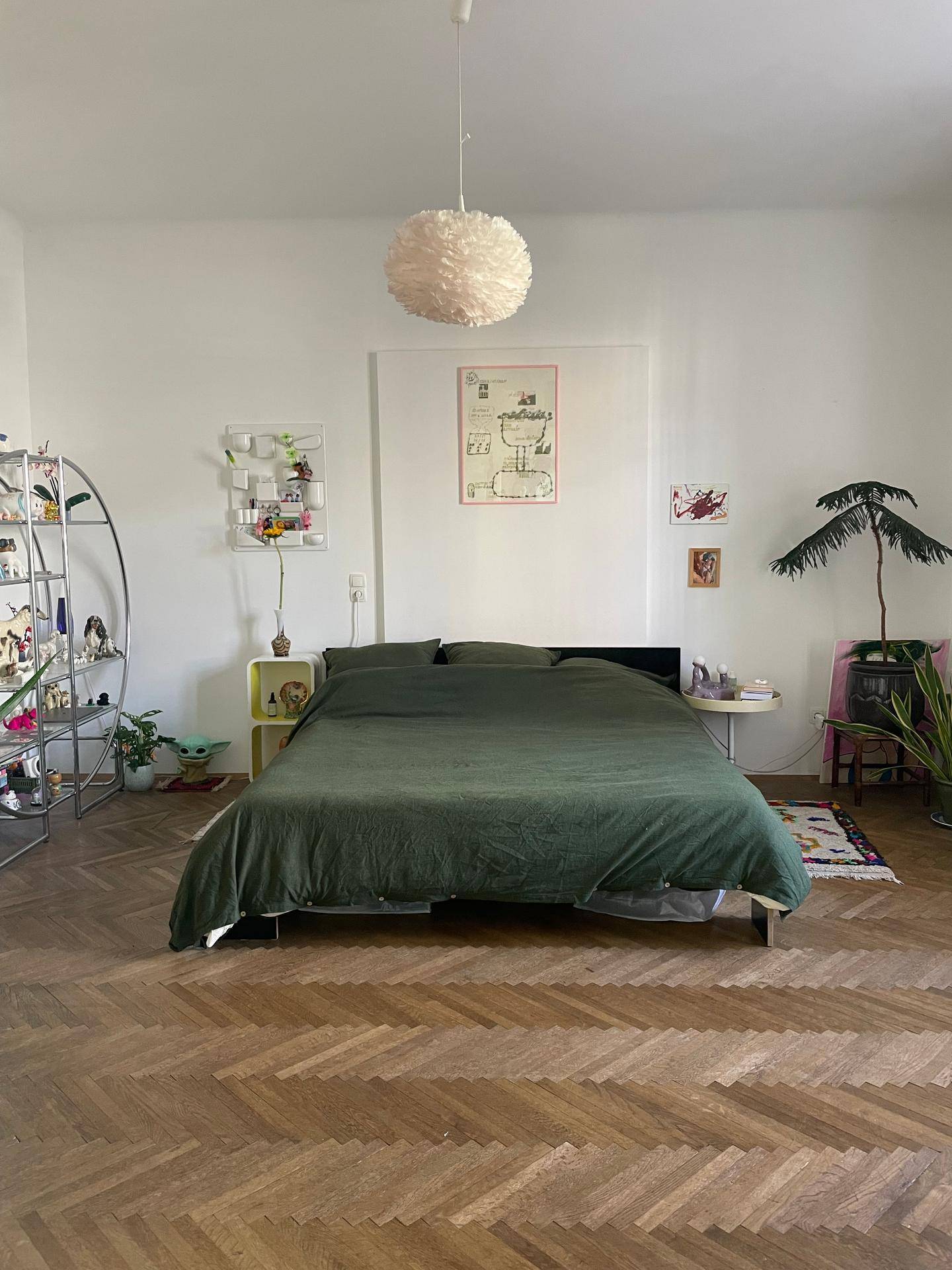 Helles Schlafzimmer mit großem Bett, Fischgrätparkett und minimalistischer Dekoration.