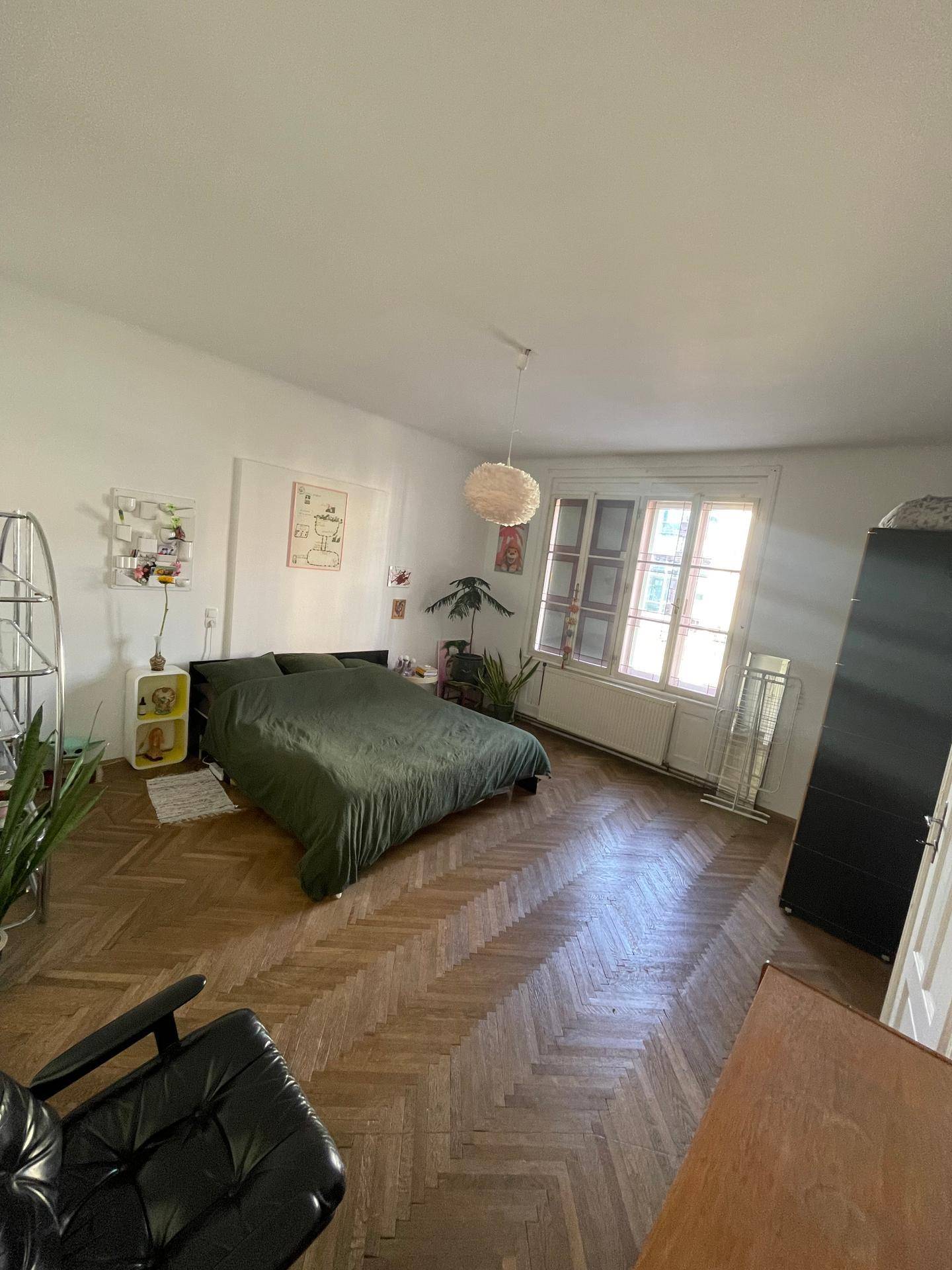 Geräumiges Schlafzimmer mit großem Fenster, Holzboden und viel Tageslicht.