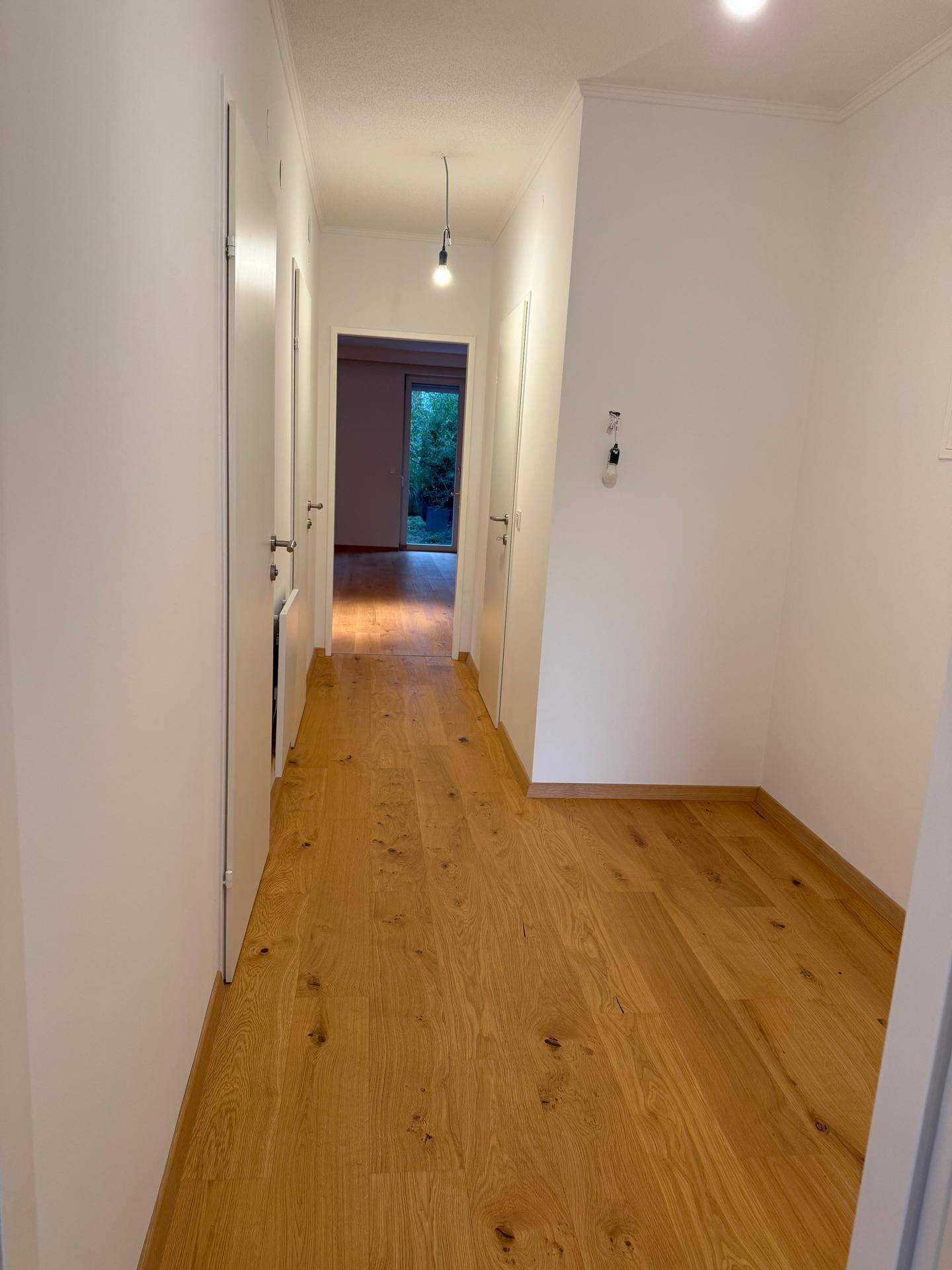 Geräumiger Flur mit hellem Holzparkett und weißen Wänden, der einen einladenden Eingangsbereich schafft.