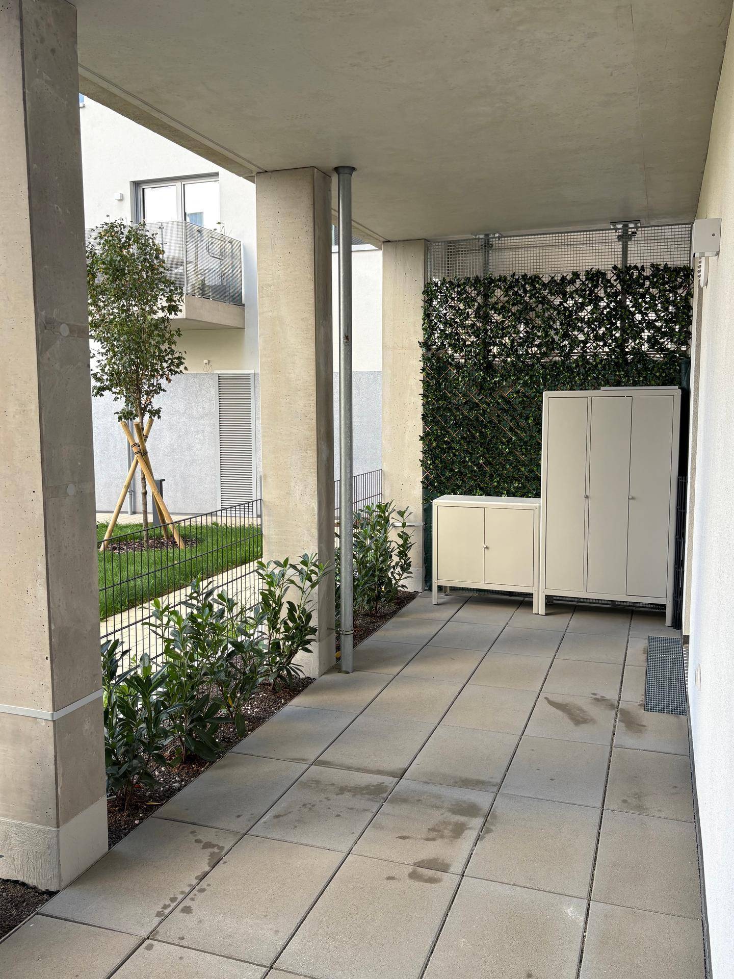 Überdachte Terrasse mit praktischen Outdoor-Schränken und Blick auf die grüne Umgebung.
