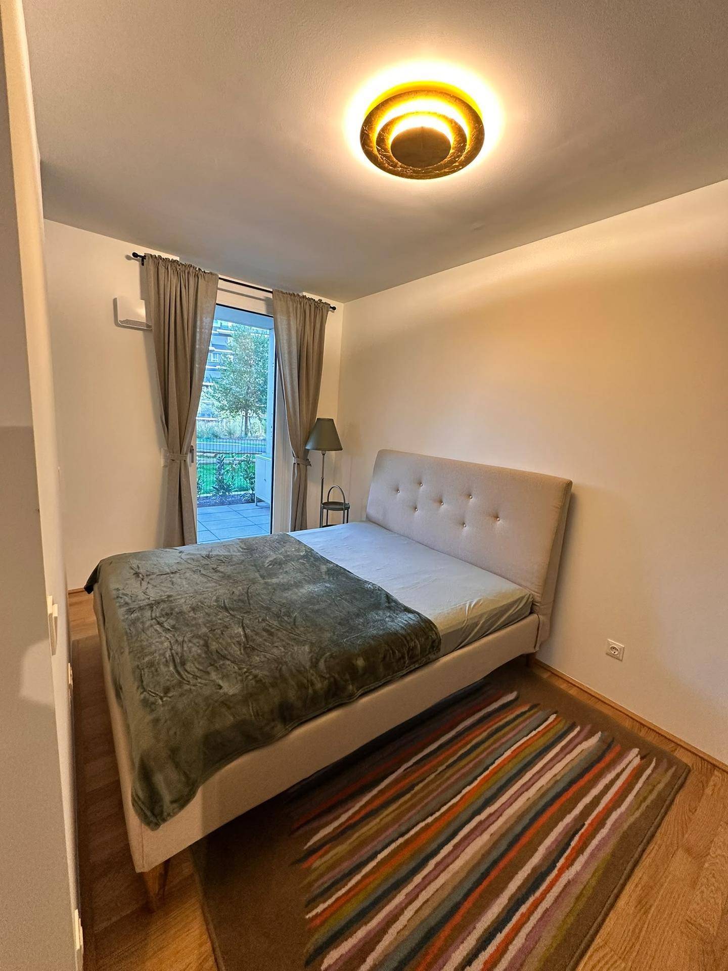 Gemütliches Schlafzimmer mit Doppelbett, Holzboden und direktem Zugang zu einem Außenbereich.