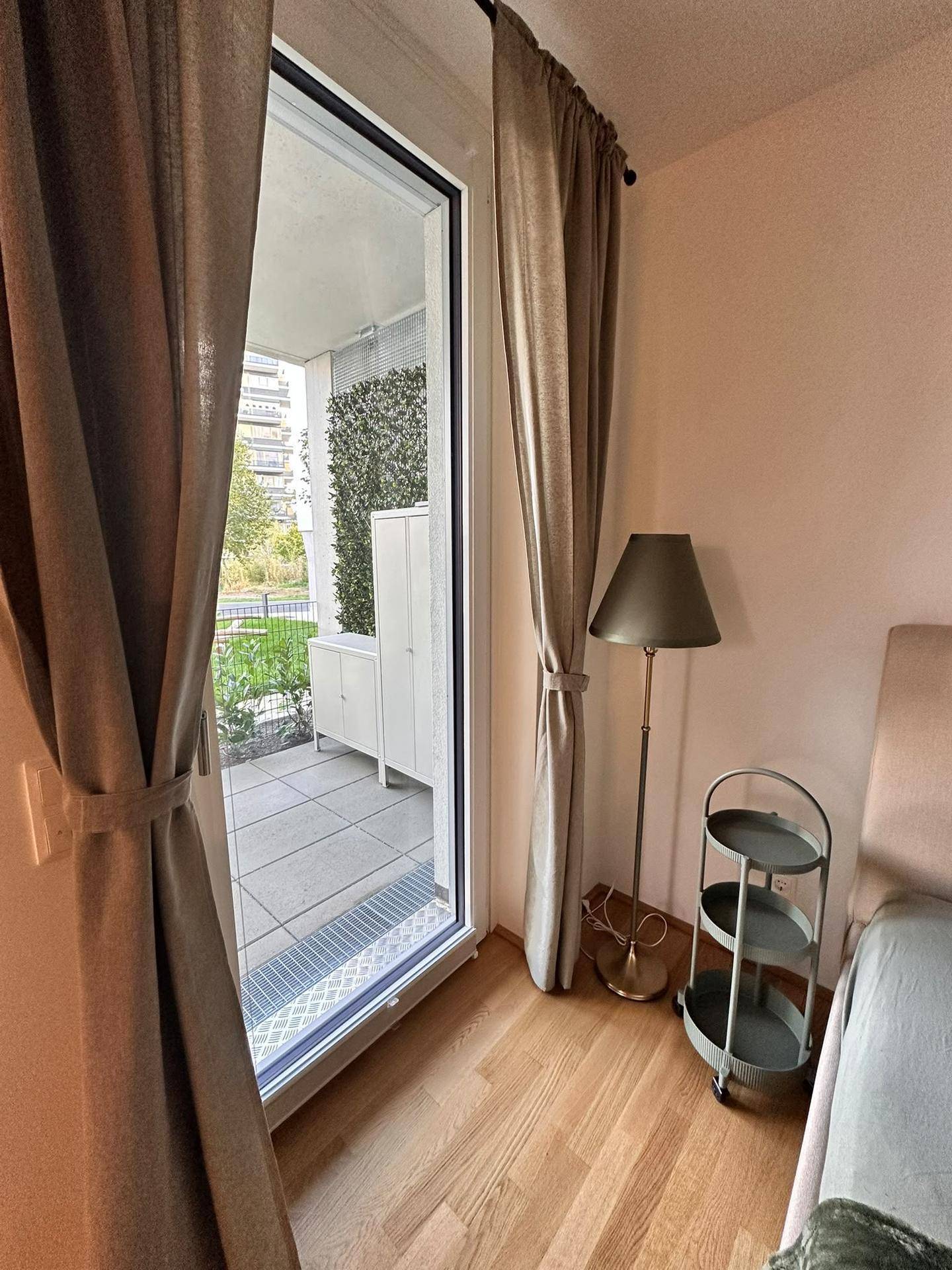 Große Glastür im Schlafzimmer bietet Zugang zur Terrasse mit Stauraum und grüner Wand.