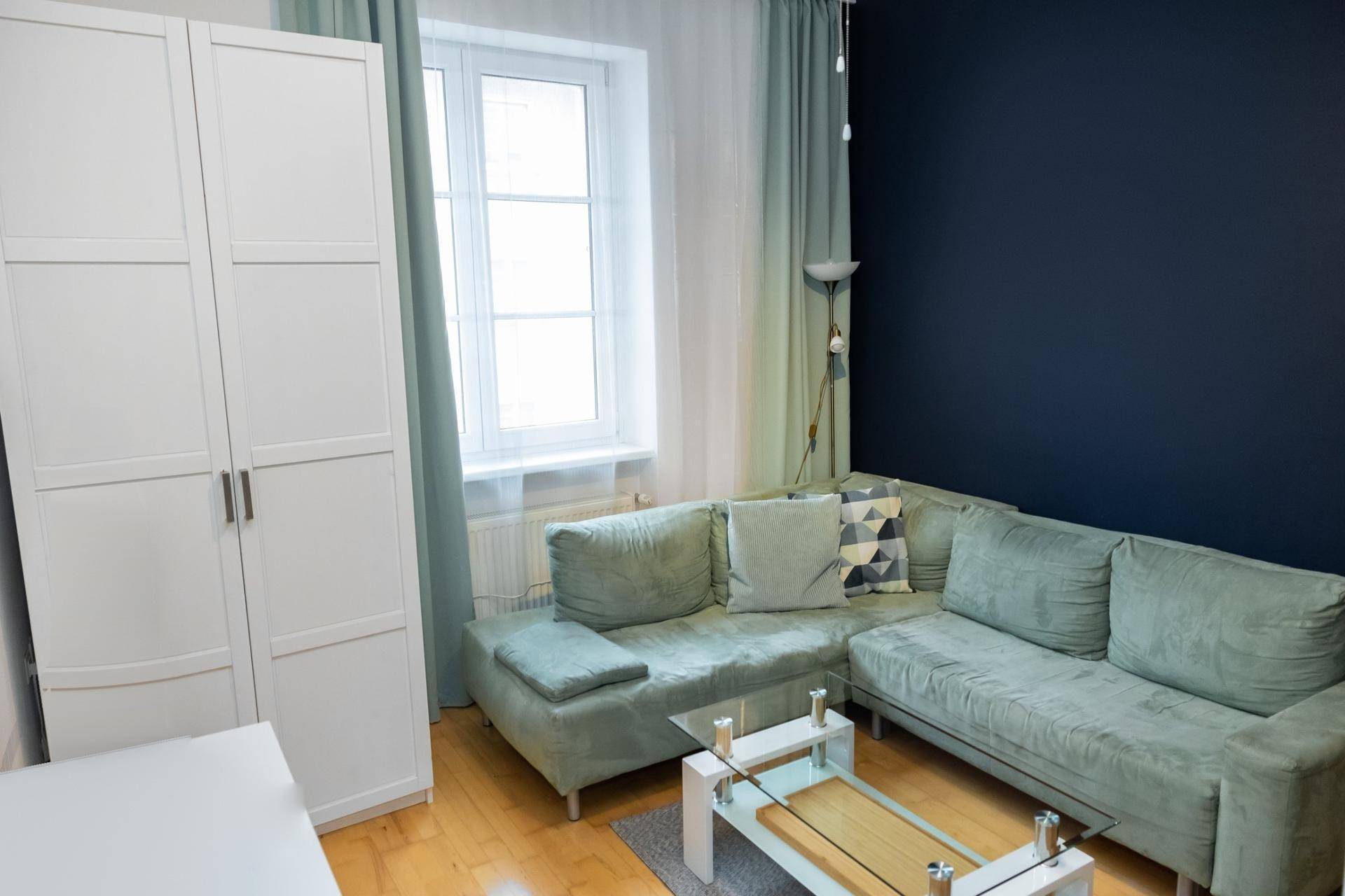 Gemütliches Wohnzimmer mit Ecksofa, Couchtisch und Fenster mit Vorhängen.