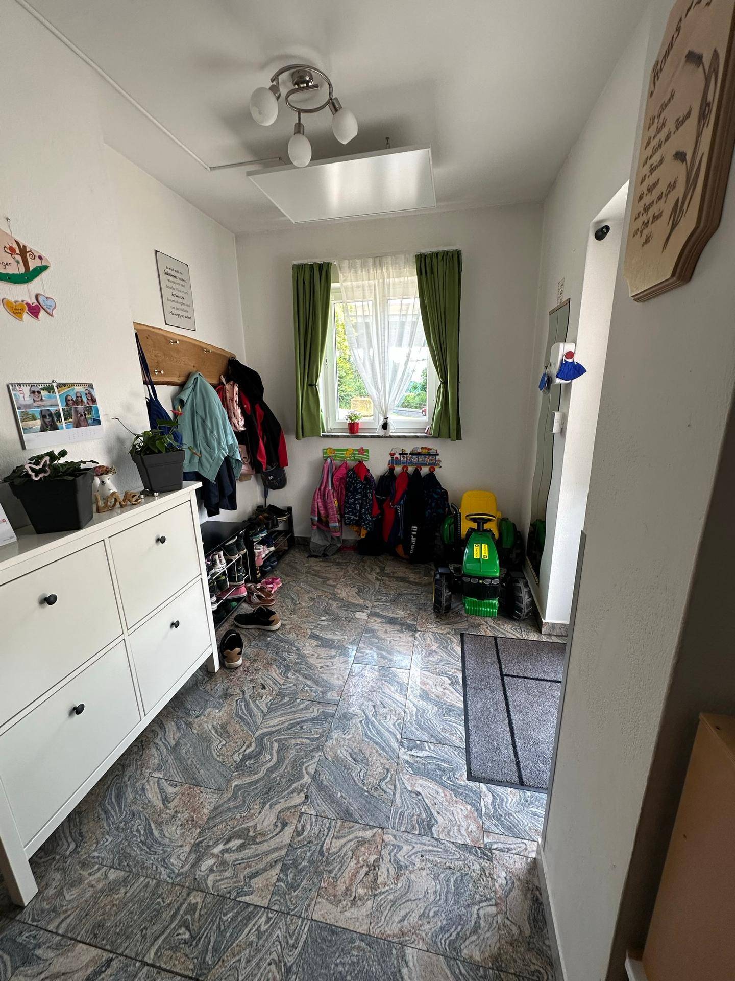 Eingangsbereich mit Fliesenboden, Garderobe und Schuhregal.