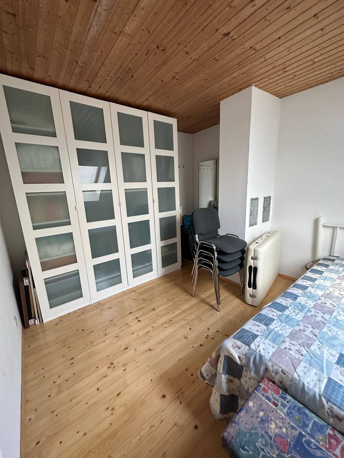 Schlafzimmer mit Holzboden, Dachschräge und großem Kleiderschrank.