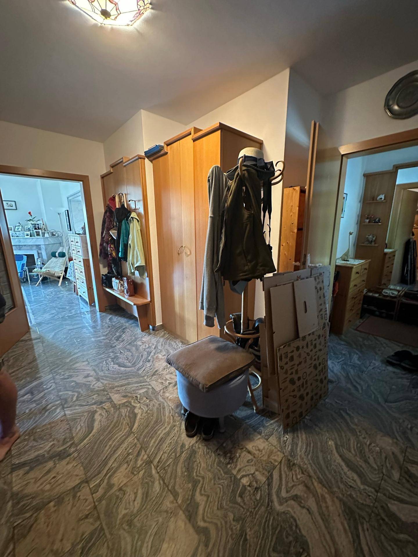 Geräumiger Flur mit Holzschränken, Garderobe und gemustertem Fliesenboden.