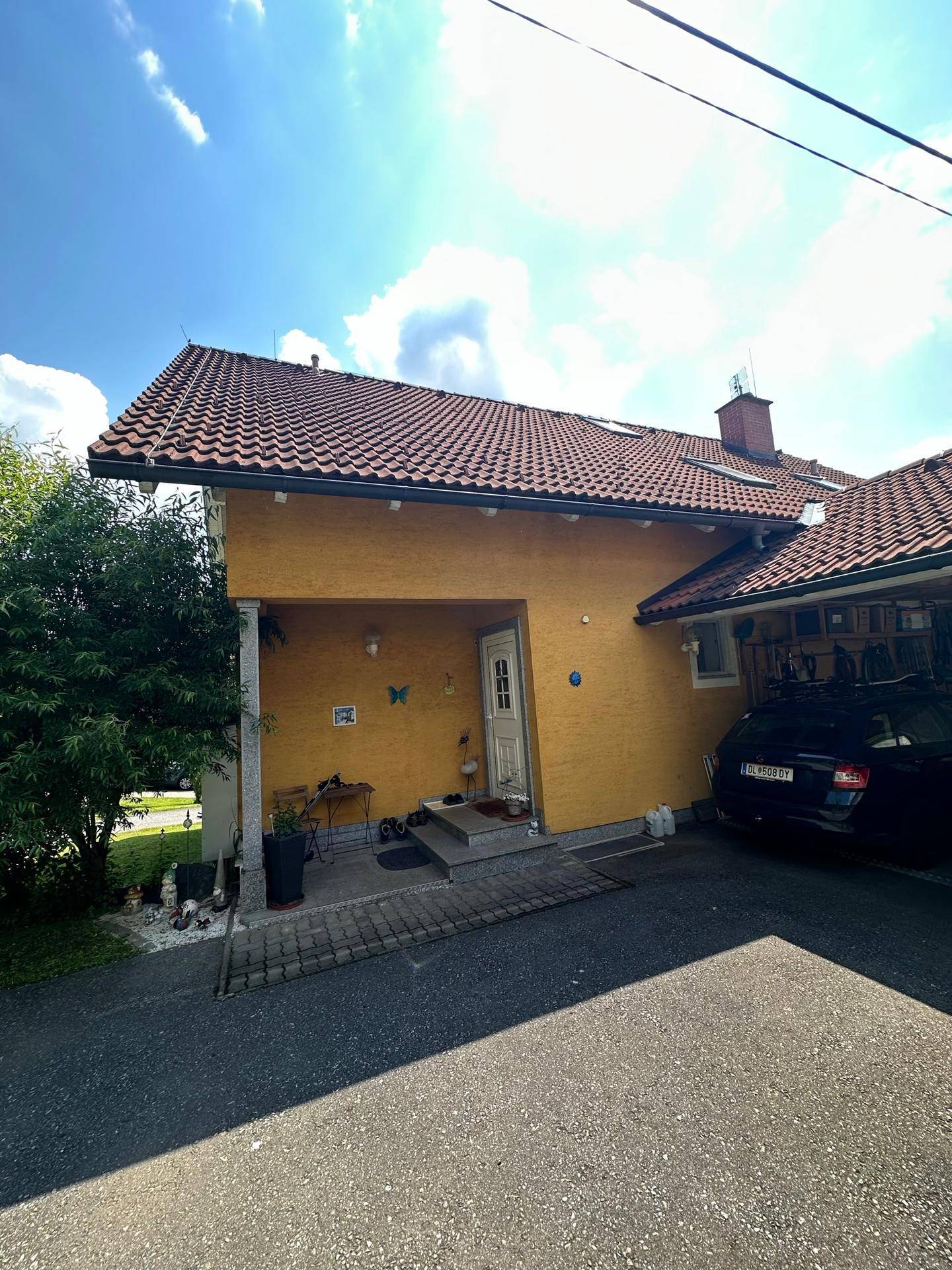 Eingangsbereich des Hauses mit überdachtem Carport und gepflasterter Zufahrt.
