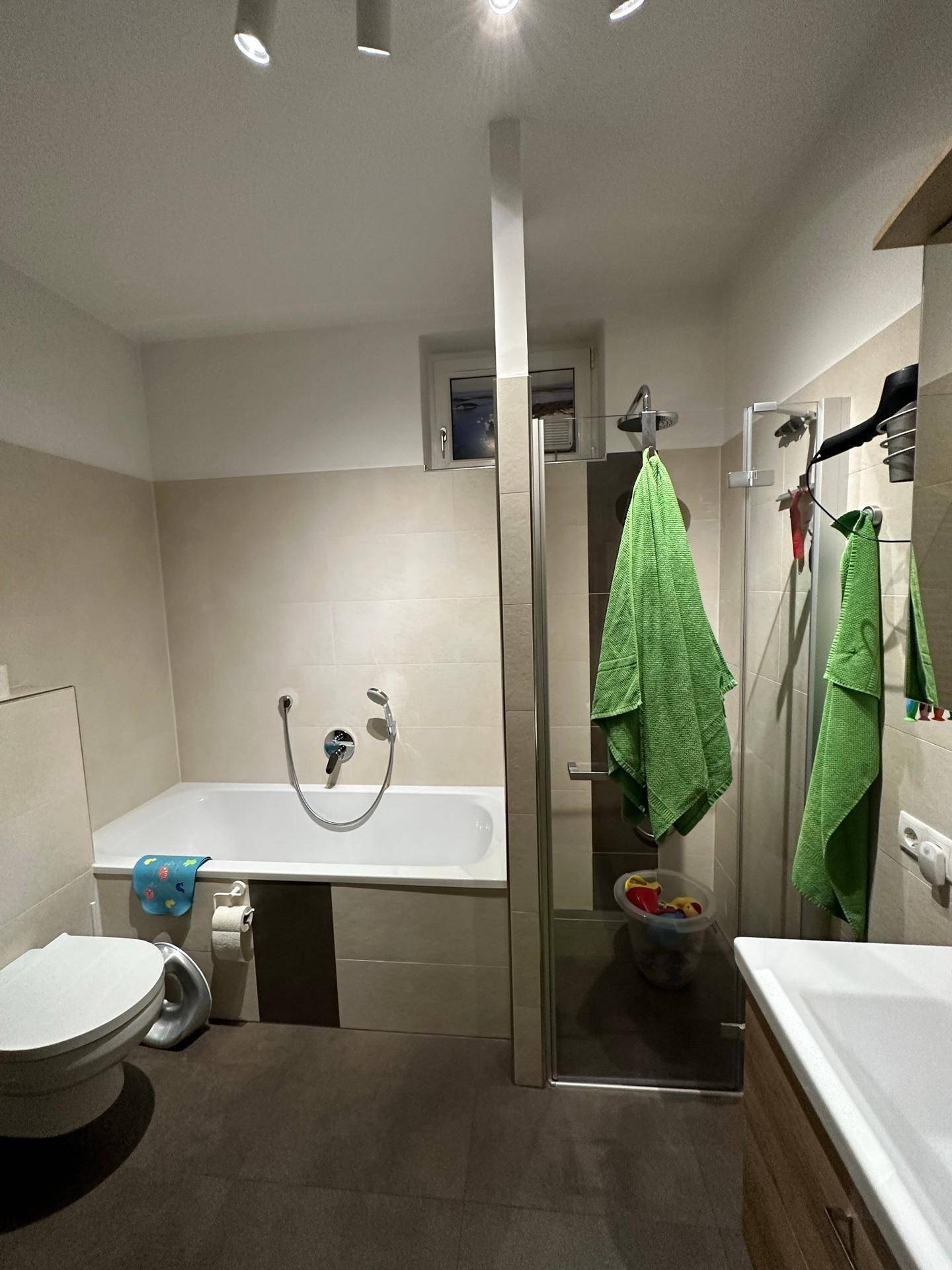 Modernes Badezimmer mit Badewanne, Duschkabine und kleinem Fenster.