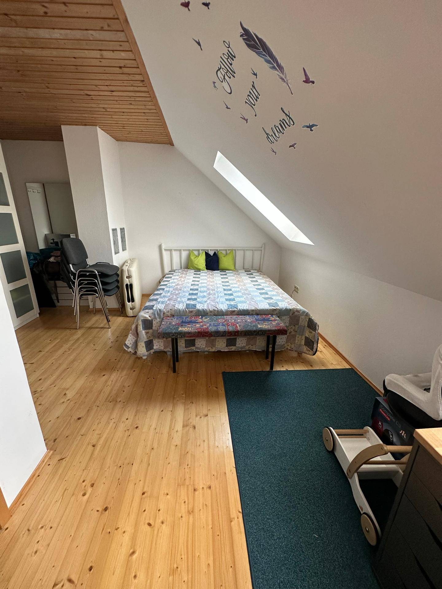 Schlafzimmer im Dachgeschoss mit Holzboden, Dachschräge und Bett.