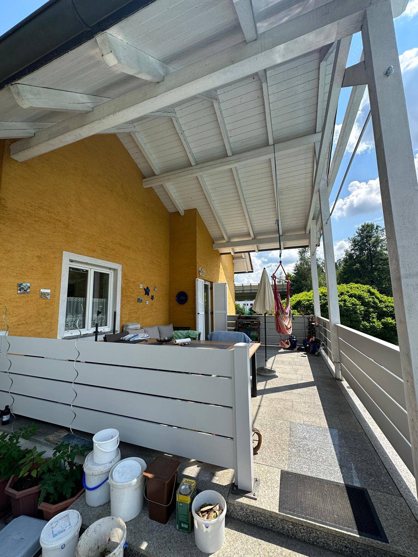 Überdachte Terrasse mit Sitzgelegenheiten und Blick ins Grüne.
