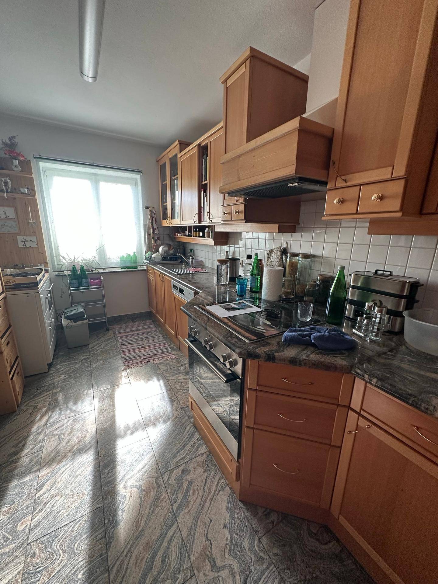 Traditionelle Holzküche mit Granitarbeitsplatten, Fenster und gemustertem Fliesenboden.