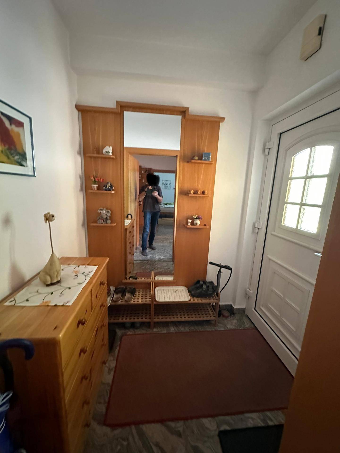 Eingangsbereich mit Holzgarderobe, Spiegel und heller Eingangstür.