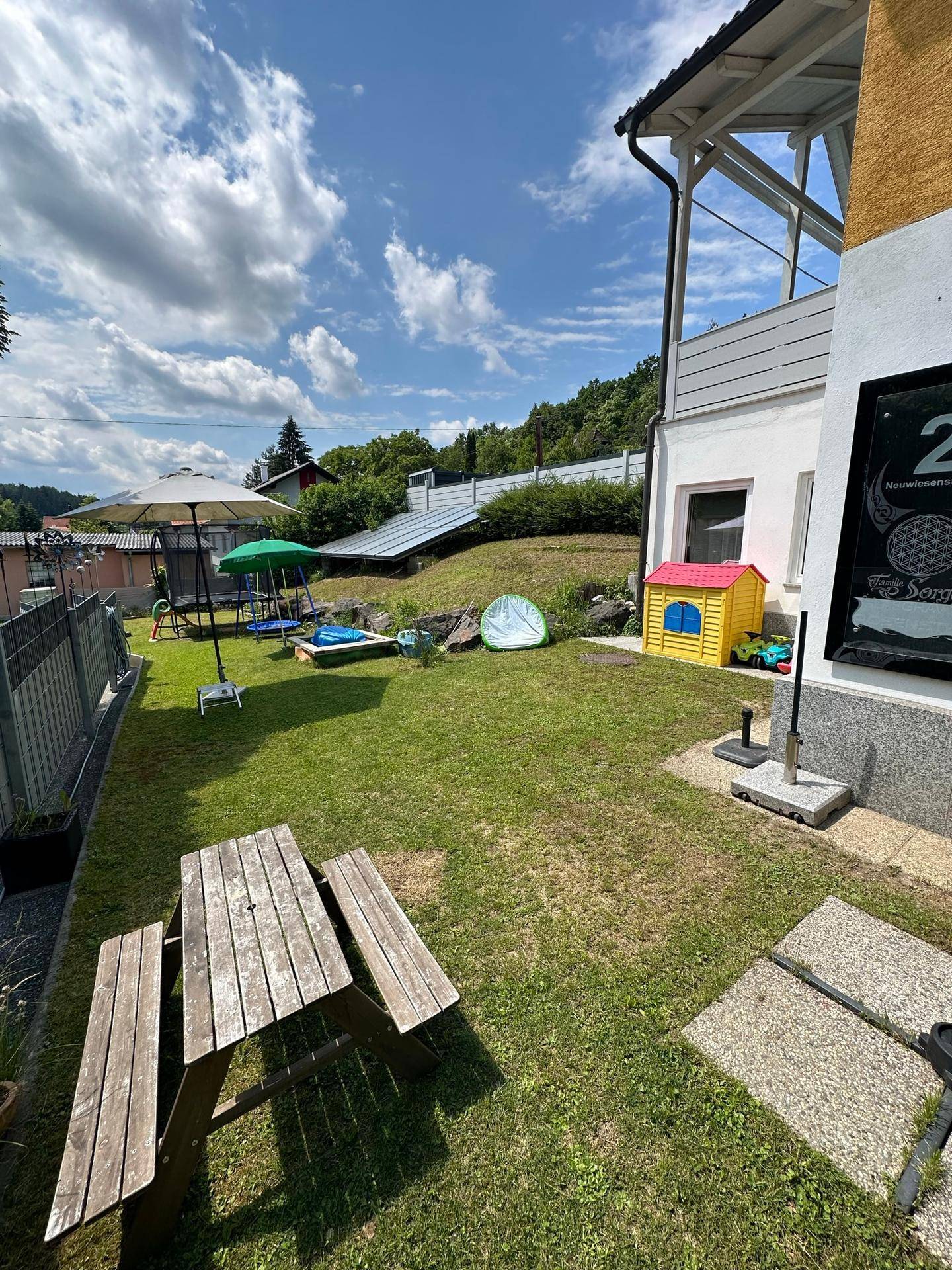 Großer Gartenbereich mit Rasen, Picknicktisch und Kinderspielgeräten.
