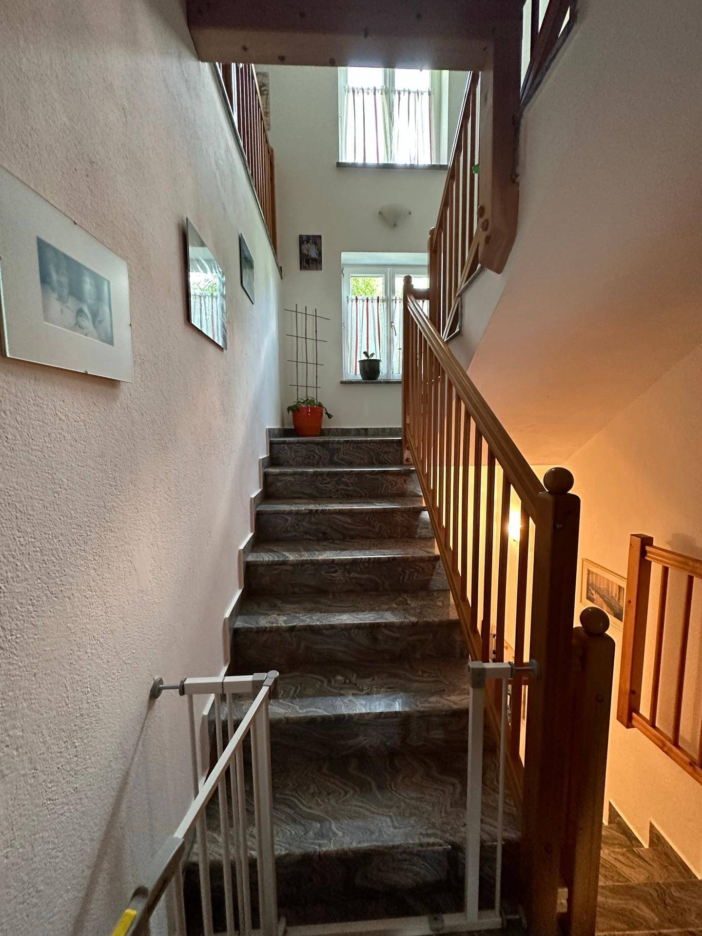 Treppenhaus mit Holzgeländer und gefliesten Stufen, das zu den oberen Etagen führt.