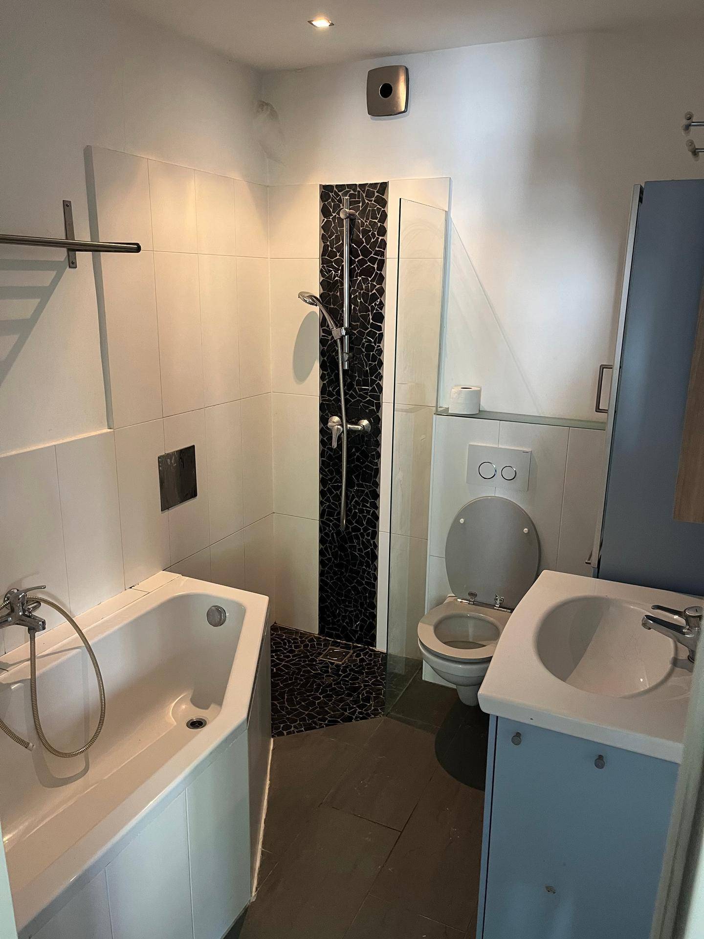 Badezimmer mit Badewanne, Duschbereich mit Mosaikfliesen und modernem WC.