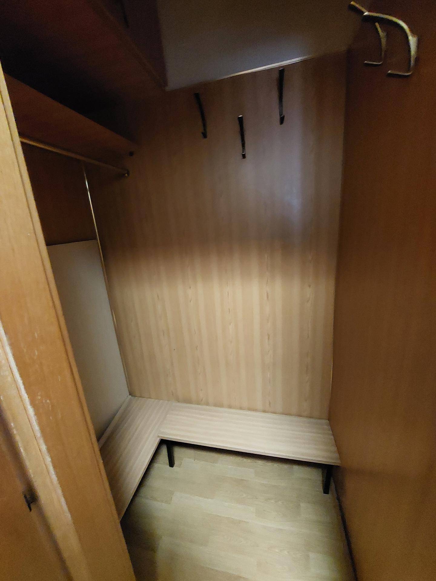 Kleiner Abstellraum oder Garderobe mit Holzwänden und Sitzbank.