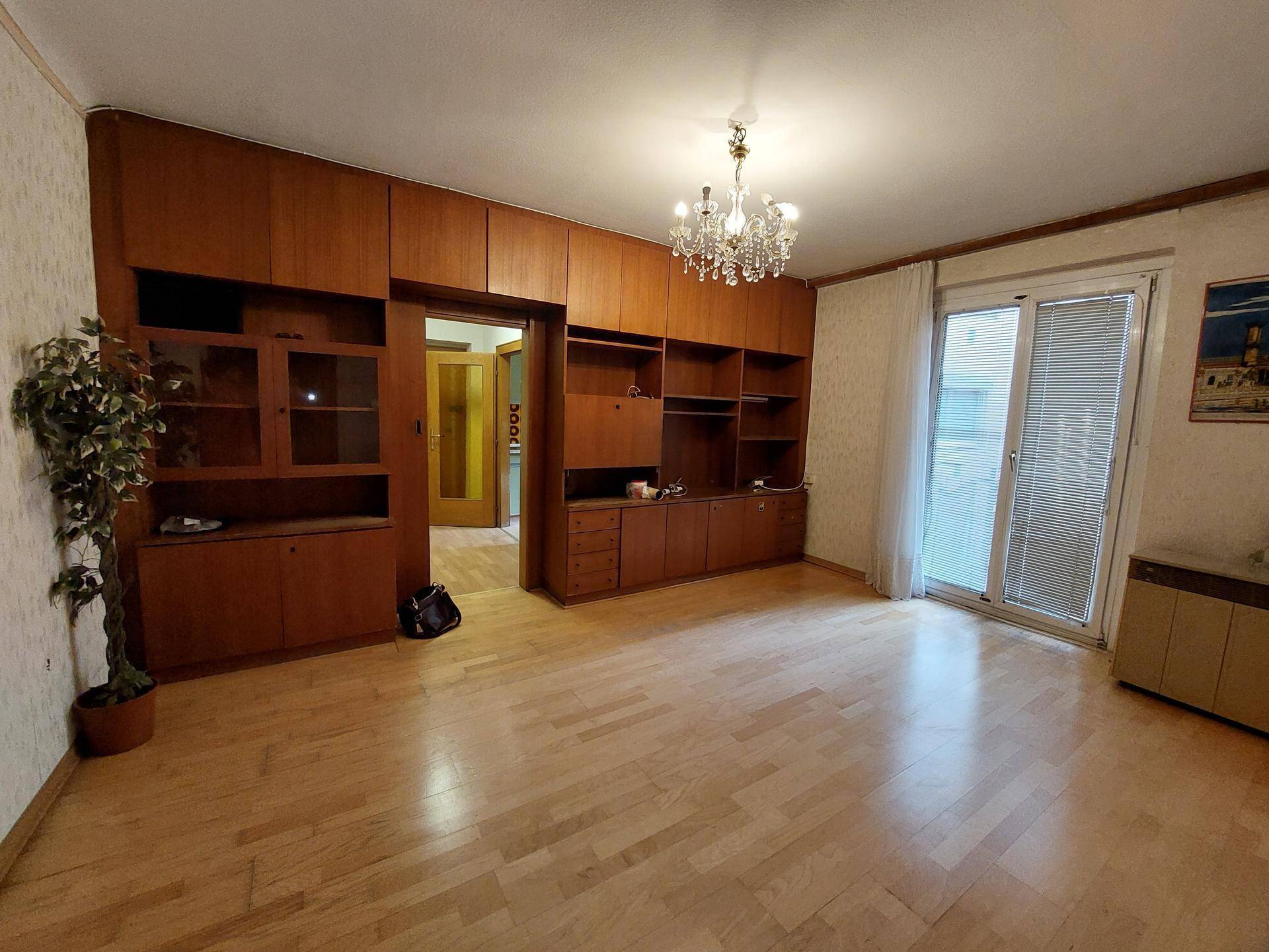 Geräumiges Wohnzimmer mit Parkettboden, Einbauschränken und Zugang zum Balkon.