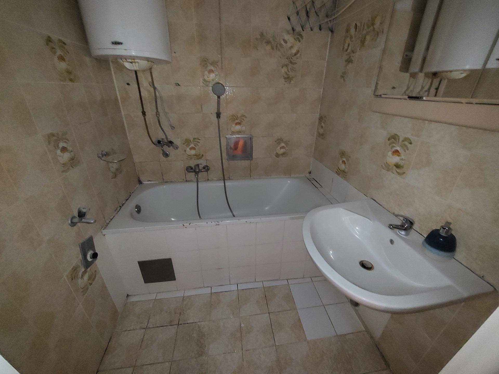 Badezimmer mit Badewanne, Waschbecken und gemusterten Fliesen an Wänden und Boden.