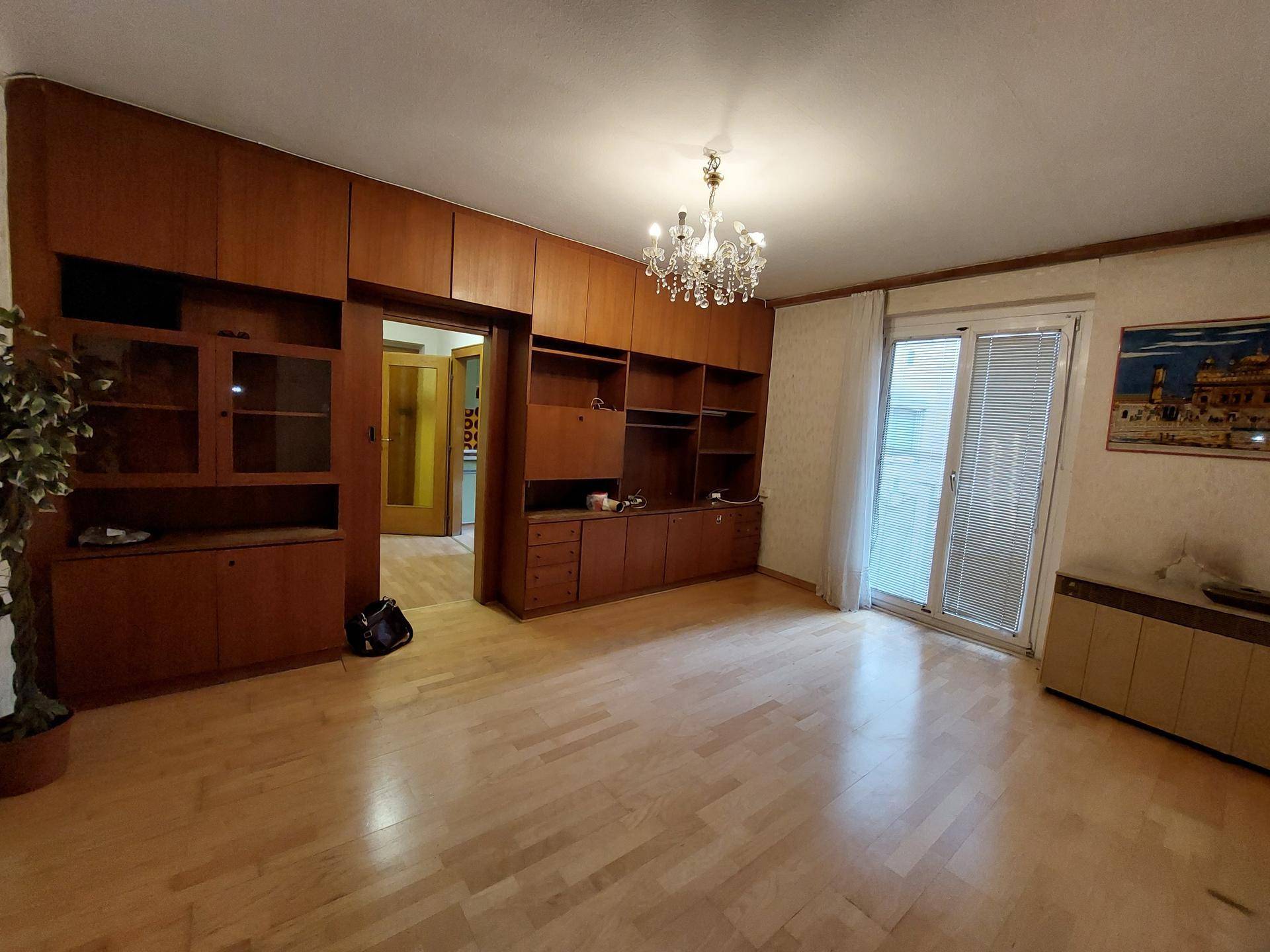 Geräumiges Wohnzimmer mit Parkettboden, Einbauschränken und Zugang zum Balkon.