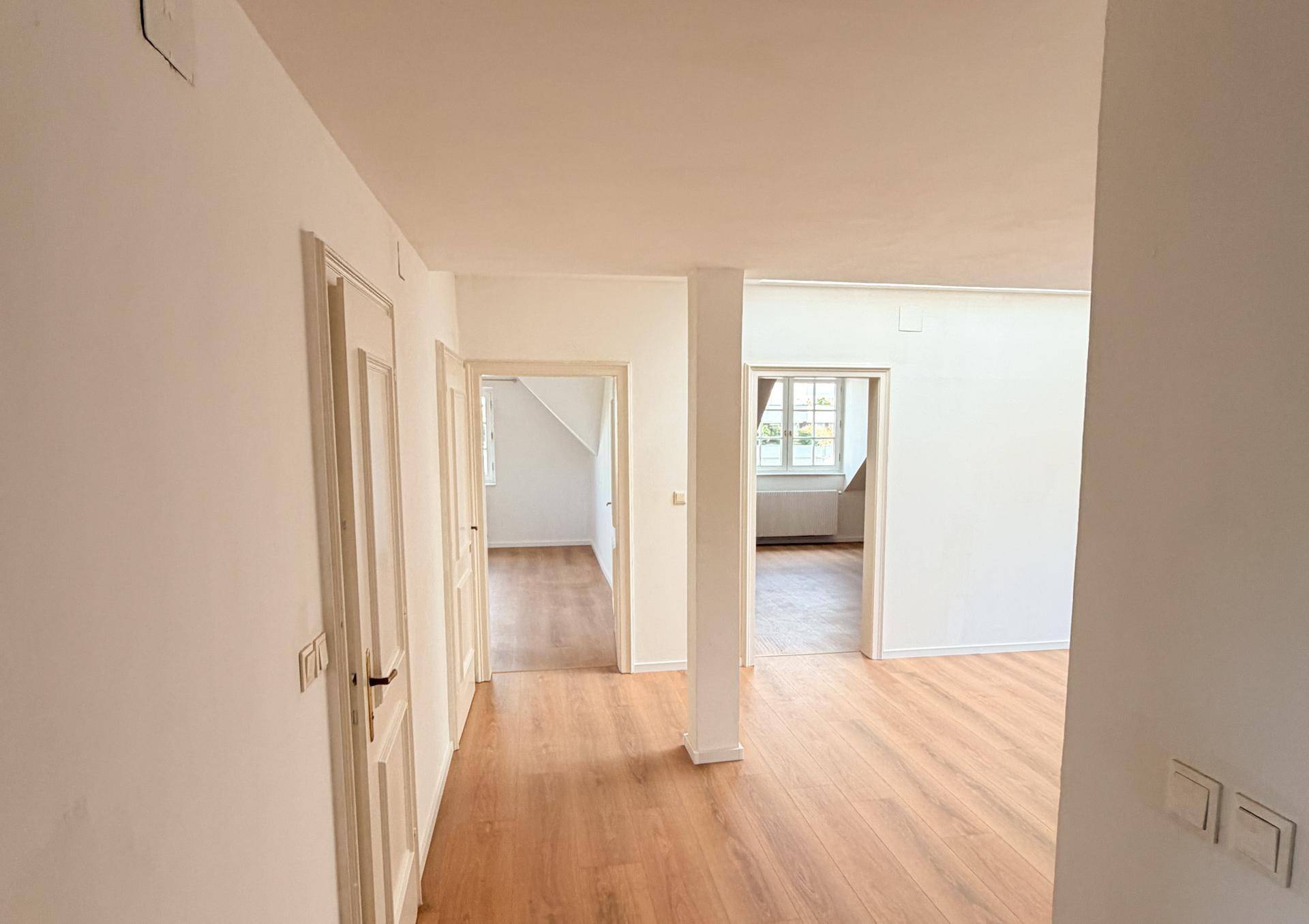 Heller Flur mit Holzboden und mehreren Türen, die zu verschiedenen Räumen führen.