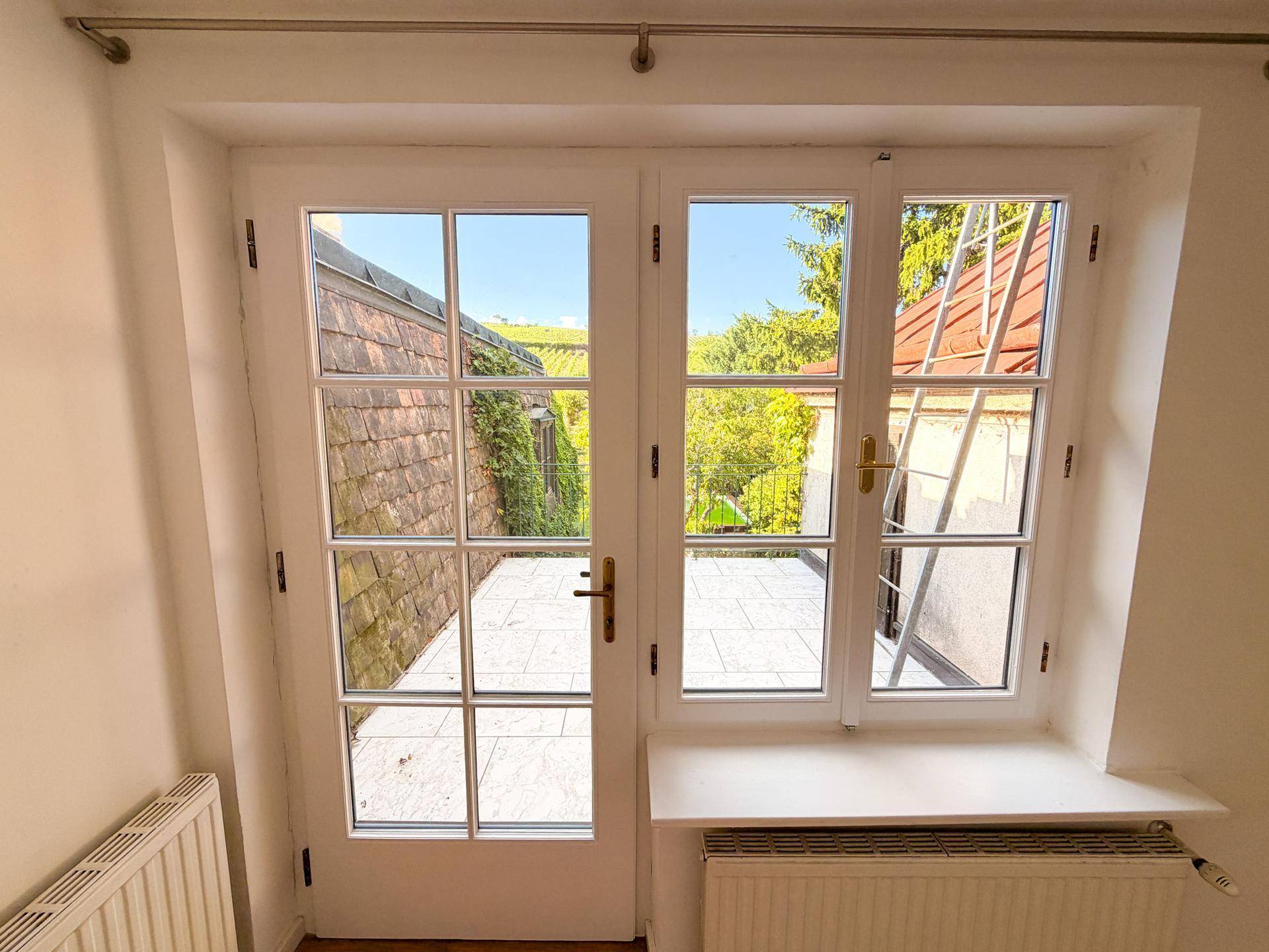 Französische Balkontür mit Blick auf den Außenbereich und eine Leiter an der Hauswand.
