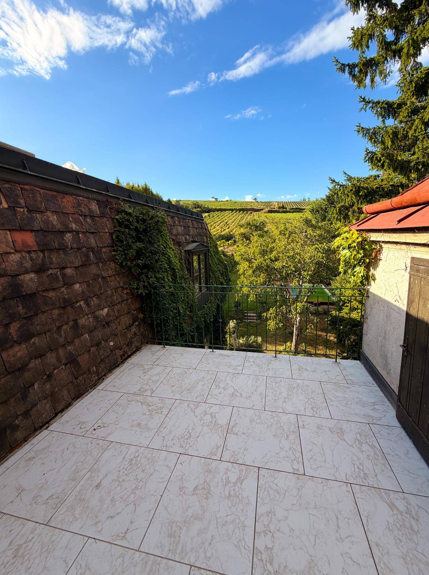Geräumige Terrasse mit Fliesenboden und weitem Blick auf die umliegenden Weinberge.