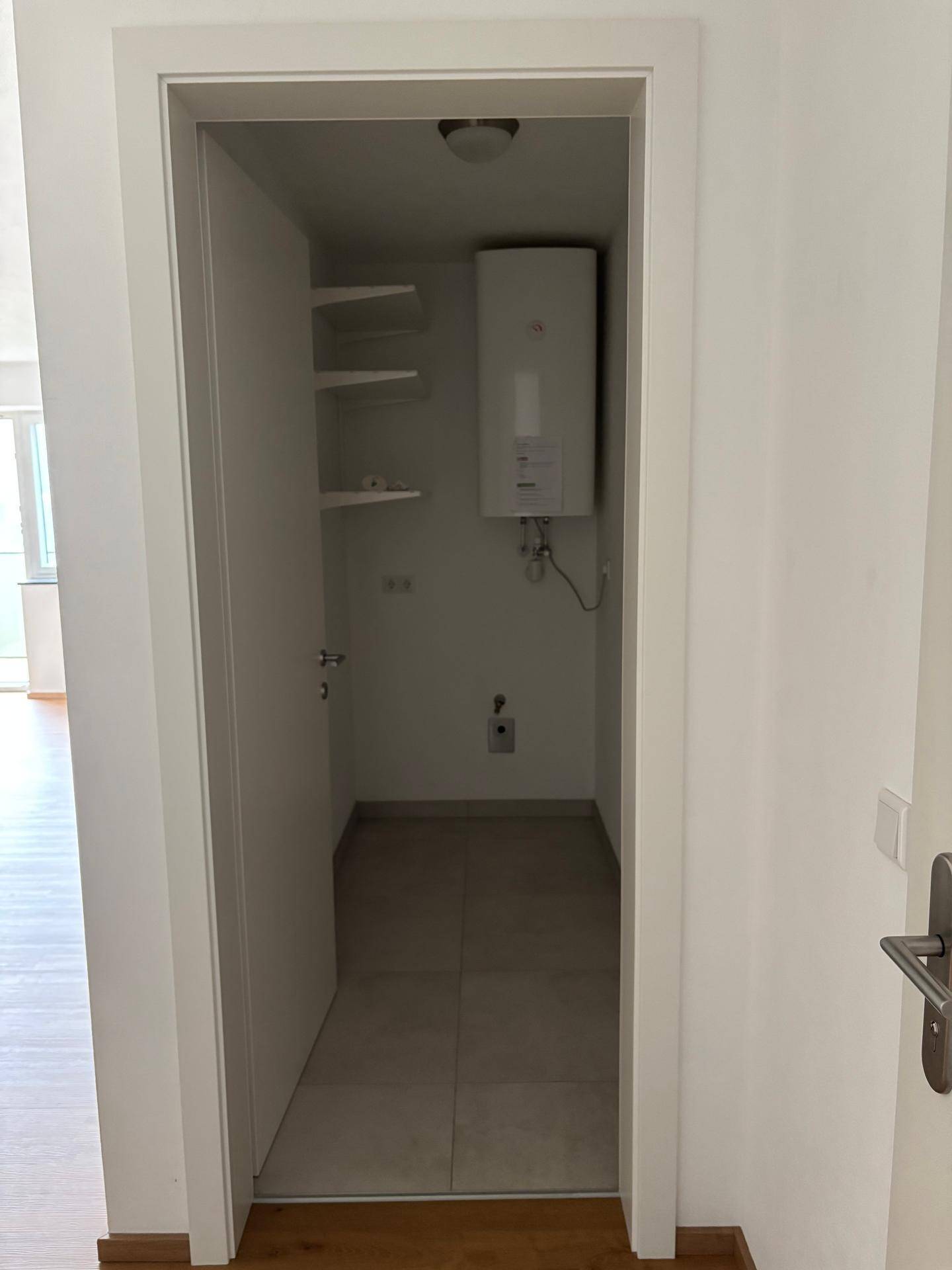 Praktischer Abstellraum mit Warmwasserbereiter und Regalen für zusätzlichen Stauraum.