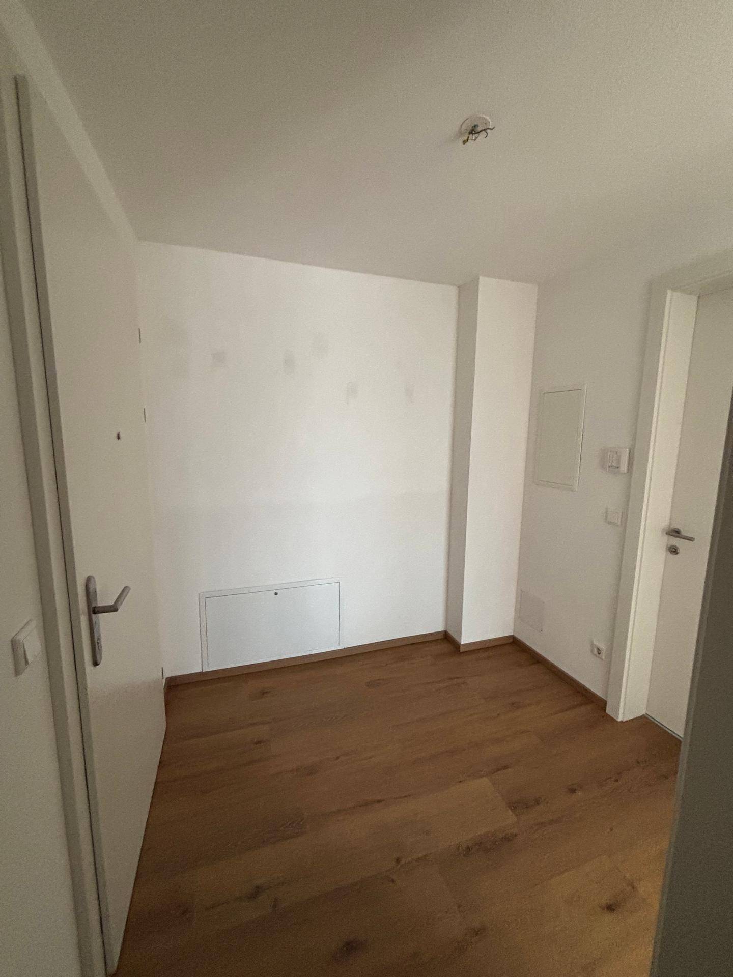 Leerer Raum mit hellem Holzboden und weißen Wänden, bereit zur individuellen Gestaltung.