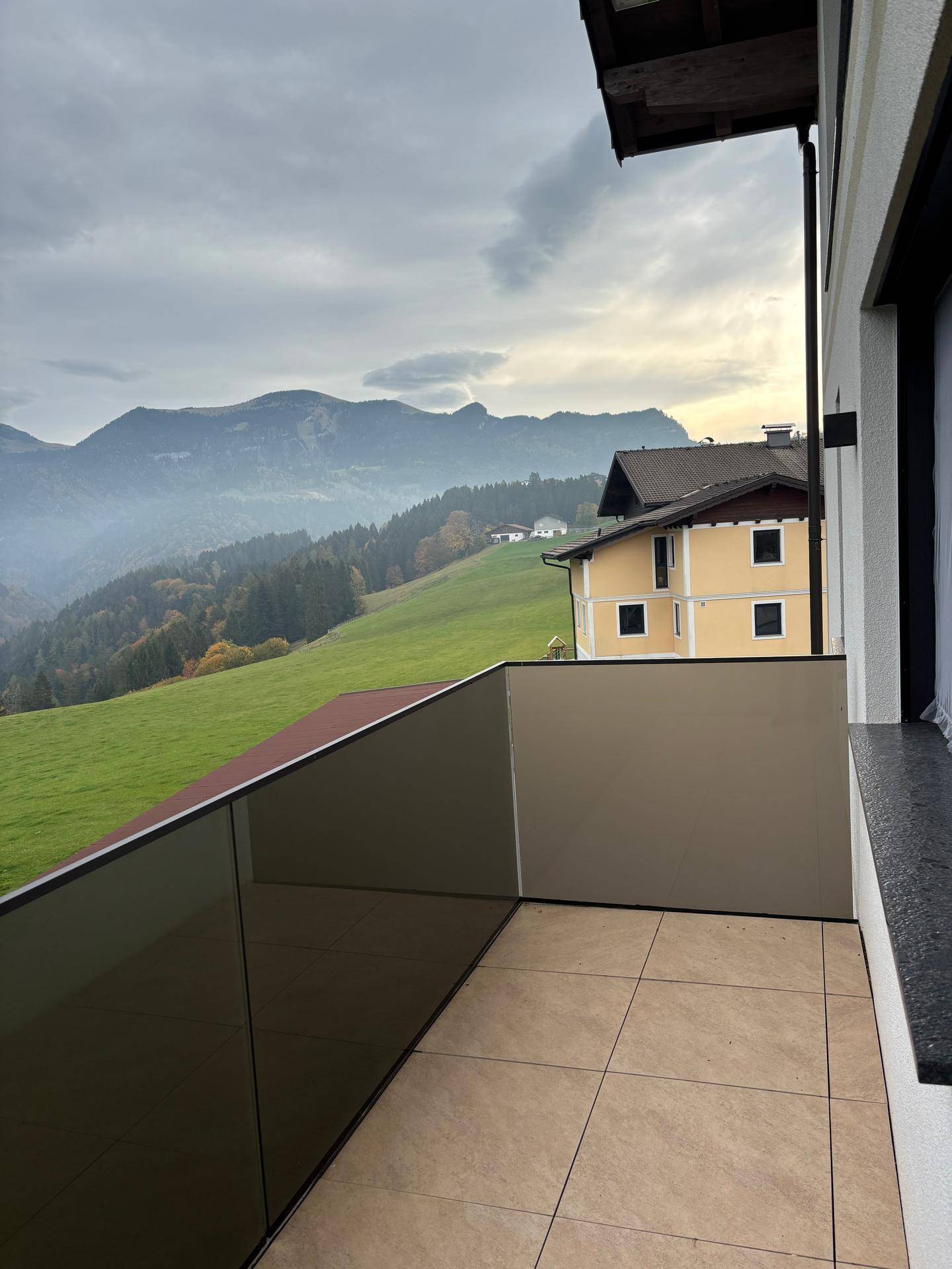 Balkon mit Glasbrüstung und atemberaubendem Panoramablick auf die umliegende Berglandschaft.