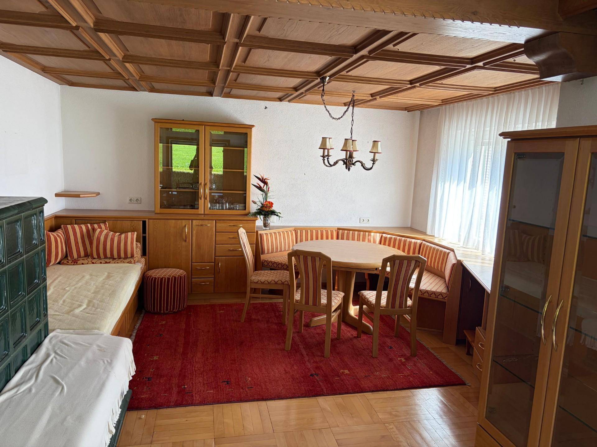 Gemütlicher Wohn-Essbereich im alpinen Stil mit Holzkassettendecke und Kachelofen.