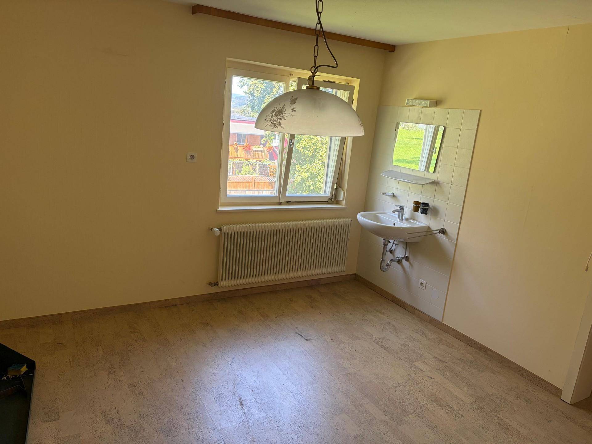 Einfacher Raum mit Waschbecken, Fenster und Linoleumboden, vielseitig nutzbar.
