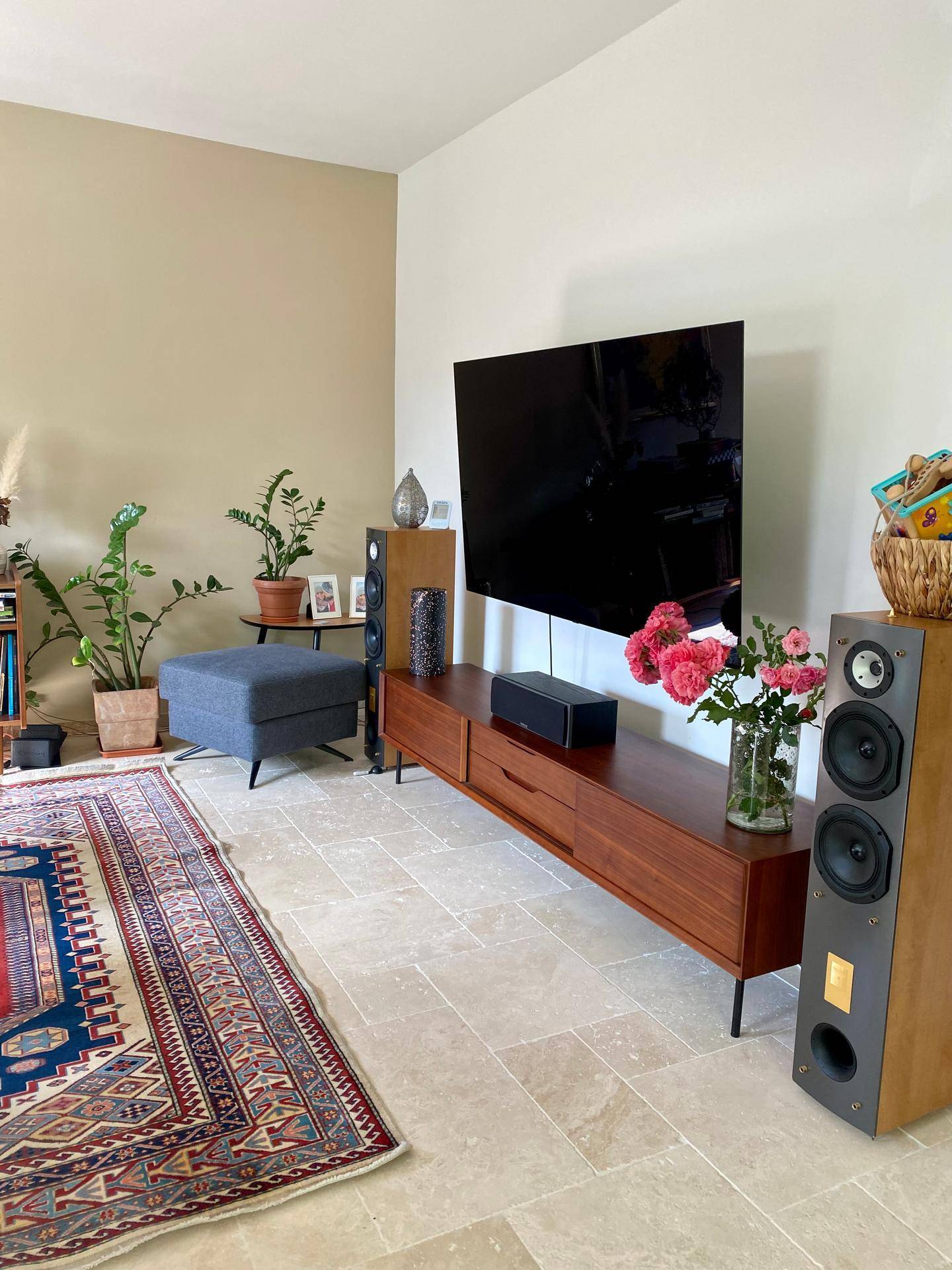 Heller Wohnbereich mit großem Fernseher, Medienschrank und Steinboden.