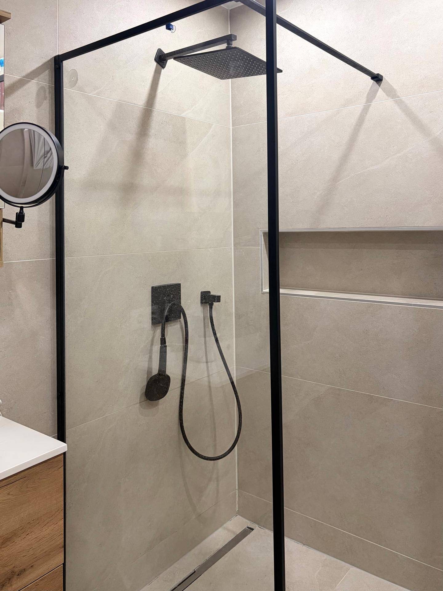 Geräumige Duschkabine mit Regendusche, schwarzen Armaturen und Glasabtrennung.