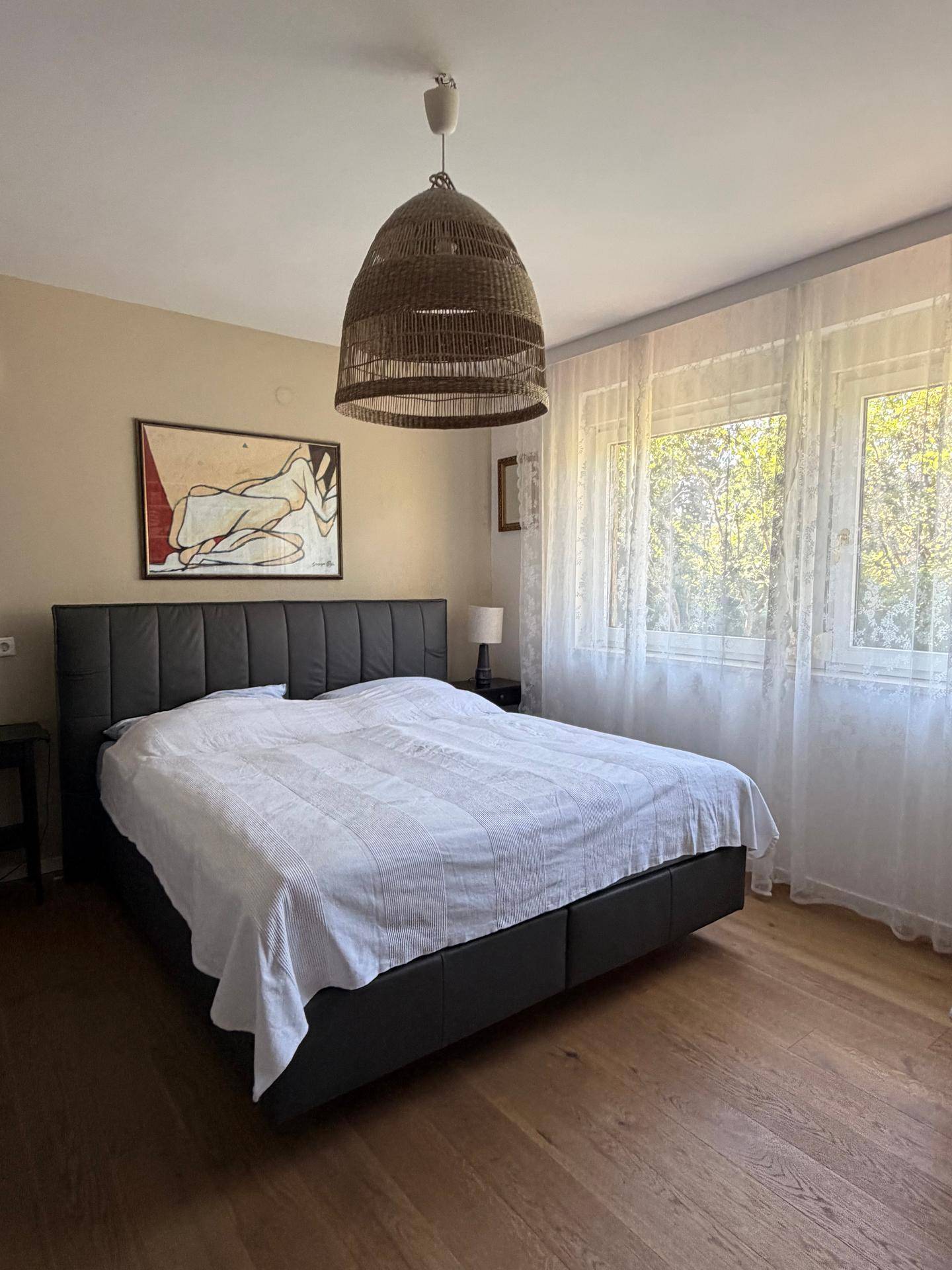 Geräumiges Schlafzimmer mit großem Doppelbett, Holzfußboden und viel Tageslicht.