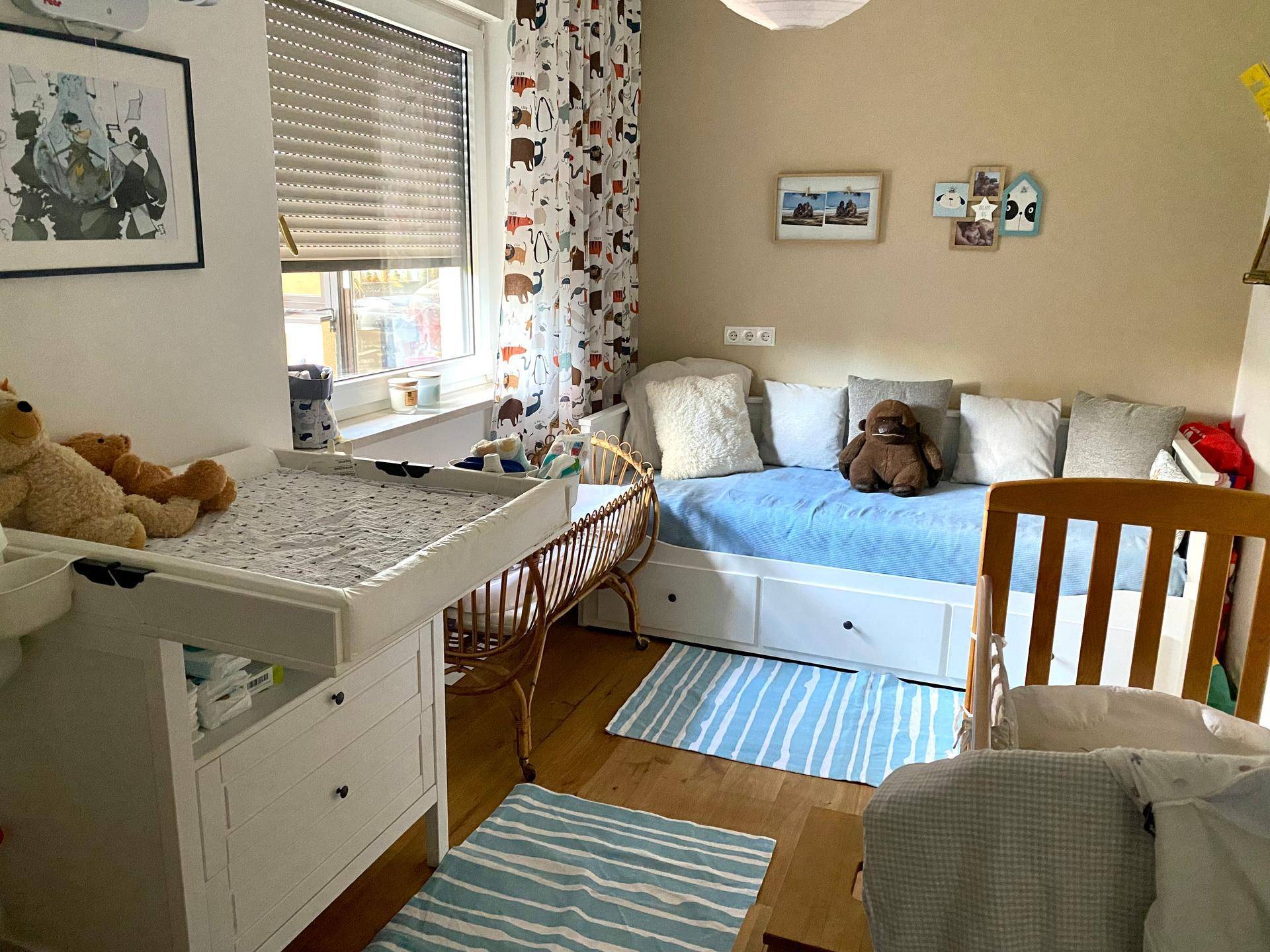 Kinderzimmer mit Wickeltisch, Tagesbett, Babybett und Holzfußboden.