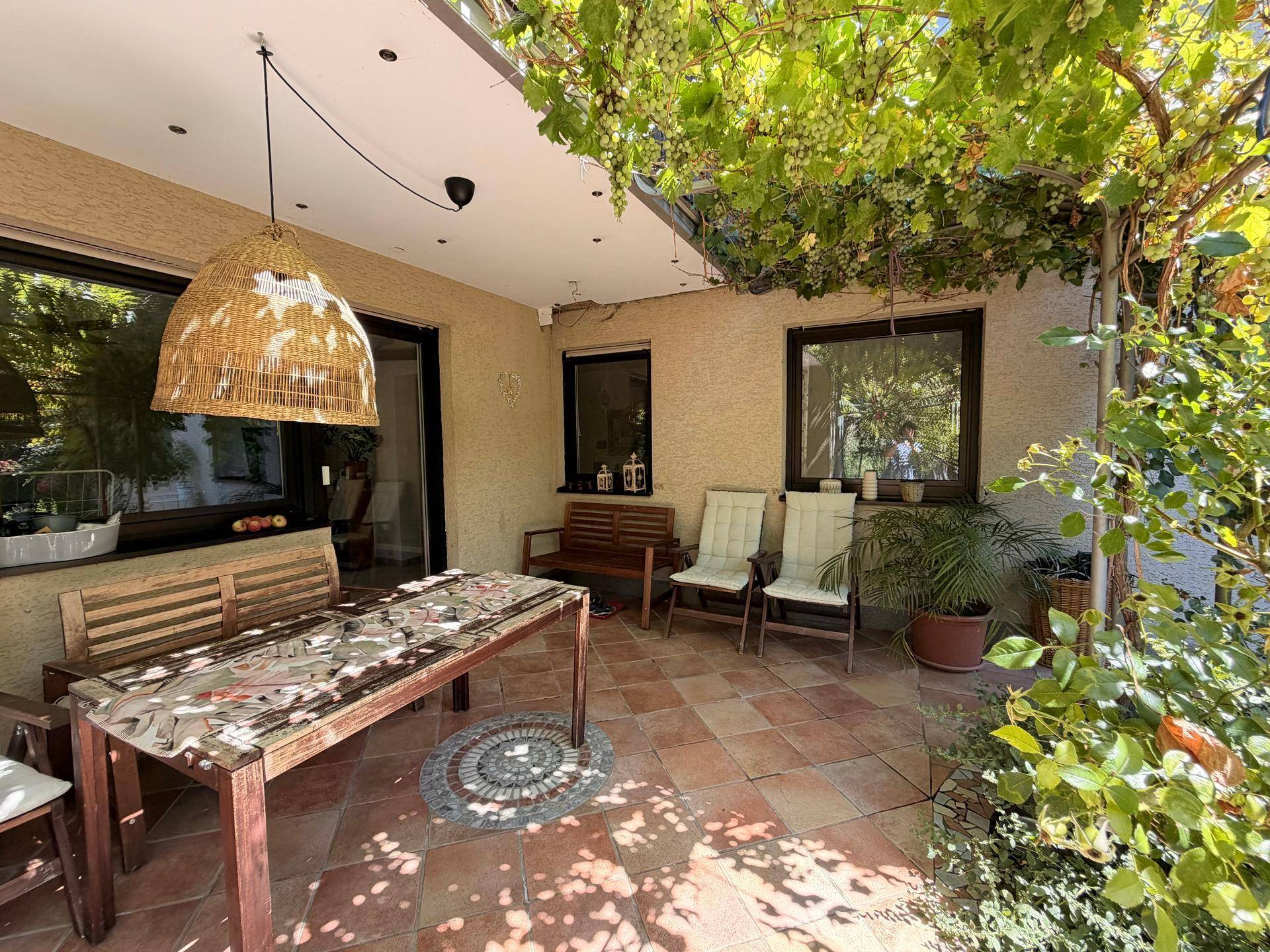 Gemütliche überdachte Terrasse mit verschiedenen Sitzgelegenheiten und vielen Pflanzen.